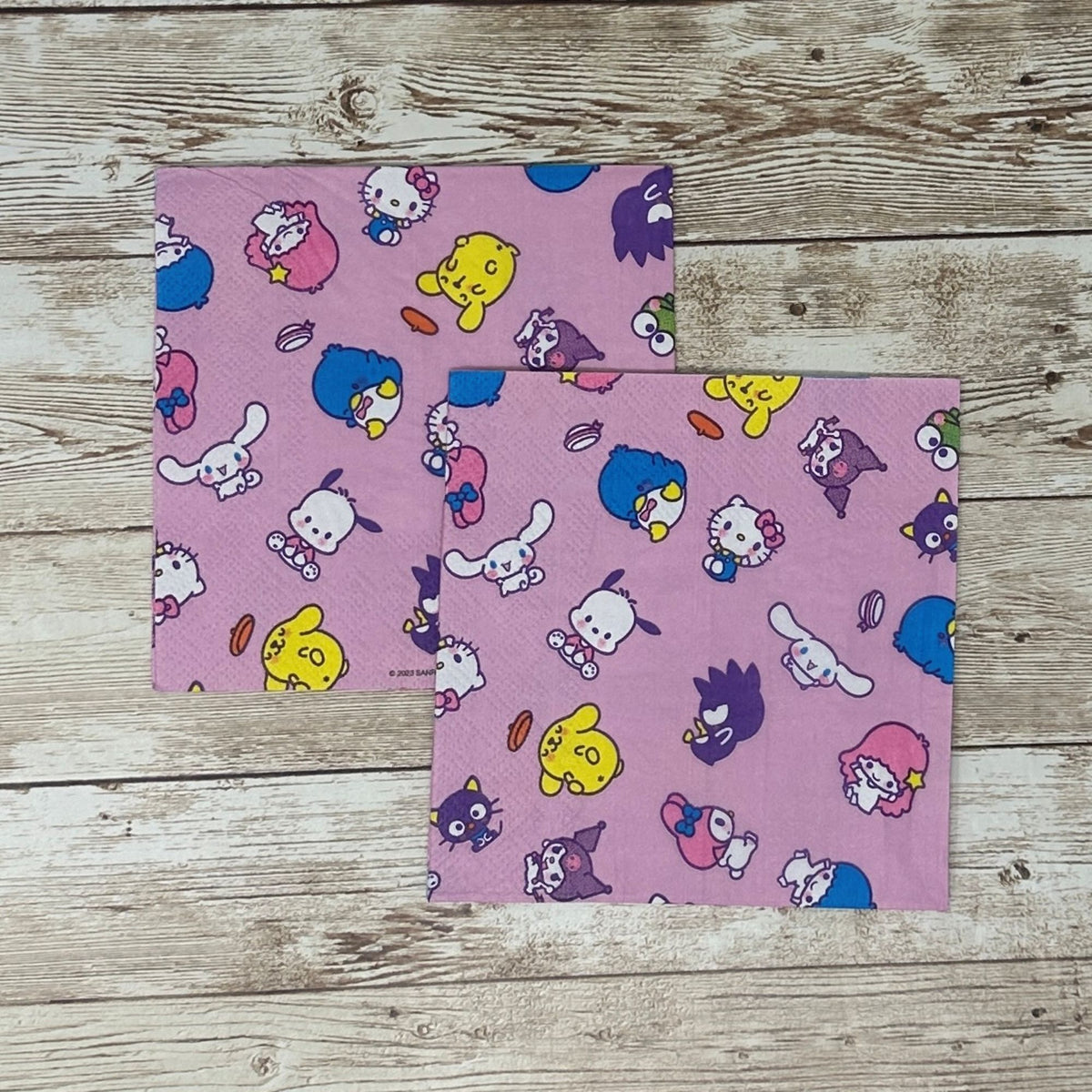 Cocktail size decoupage paper napkin featuring the Sanrio character family including Hello Kitty Cinnamoroll My Melody Pompompurin and Badtz-Maru scattered across a sweet lavender pink background set of 2