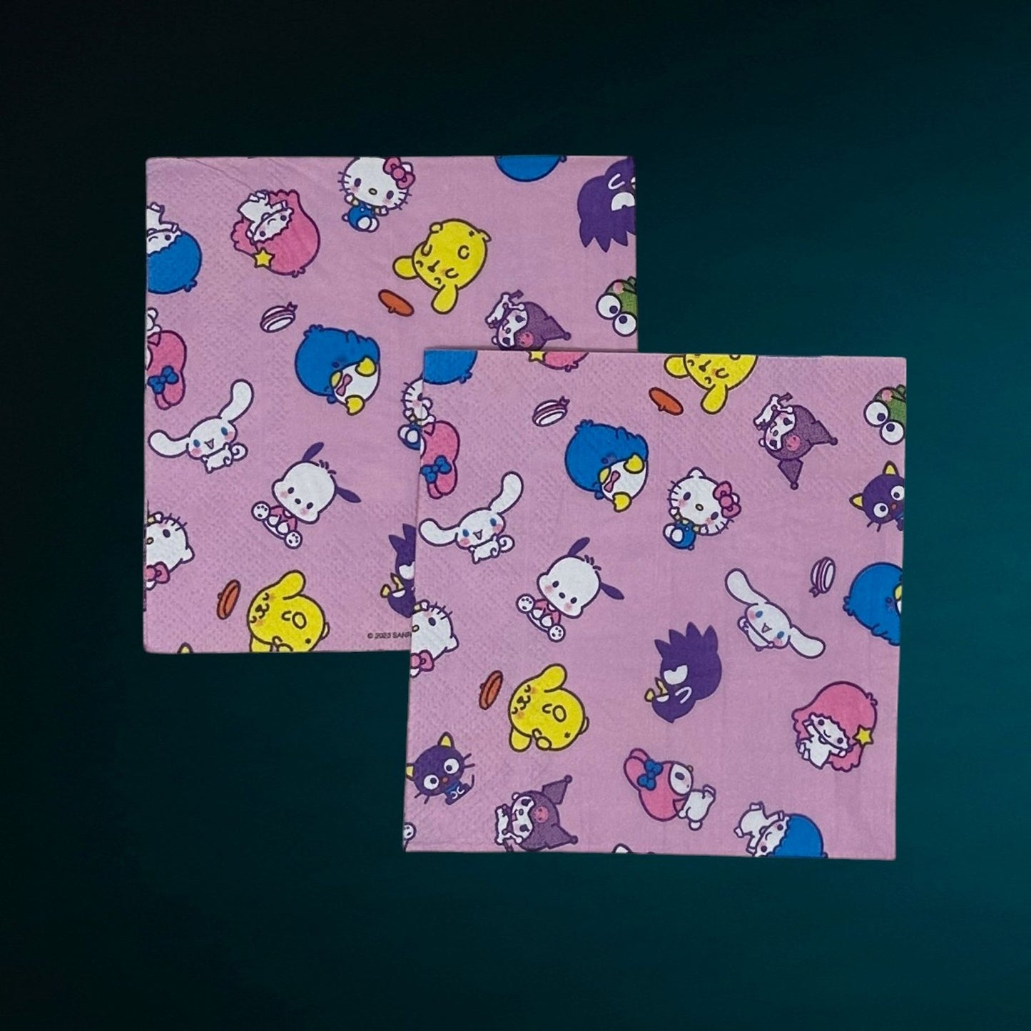 Cocktail size decoupage paper napkin featuring the Sanrio character family including Hello Kitty Cinnamoroll My Melody Pompompurin and Badtz-Maru scattered across a sweet lavender pink background set of 2