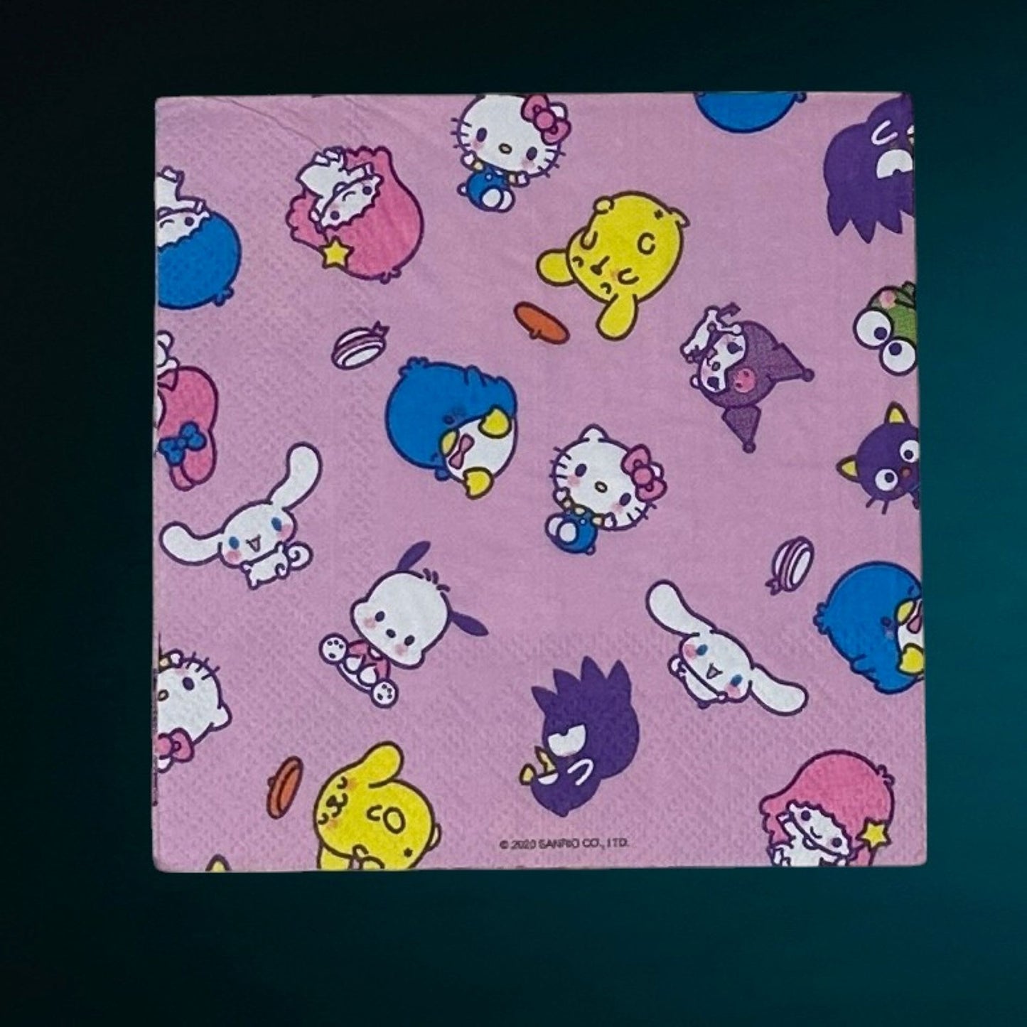 Cocktail size decoupage paper napkin featuring the Sanrio character family including Hello Kitty Cinnamoroll My Melody Pompompurin and Badtz-Maru scattered across a sweet lavender pink background set of 2