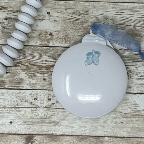 White metal ornament showing blue booties on the back of baby's first christmas ornament.