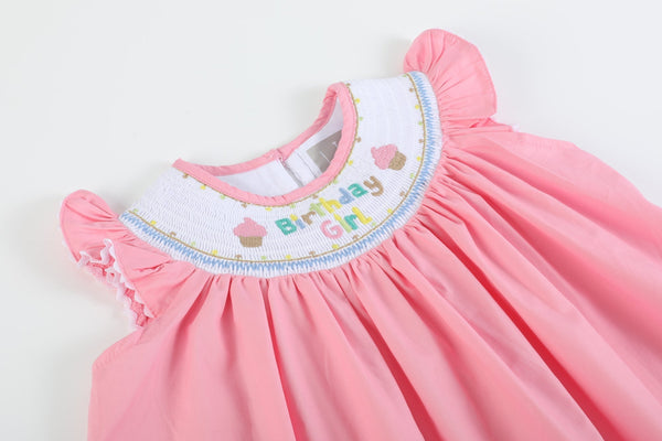 Pink smocked dress that has cupcakes and says Birthday Girl