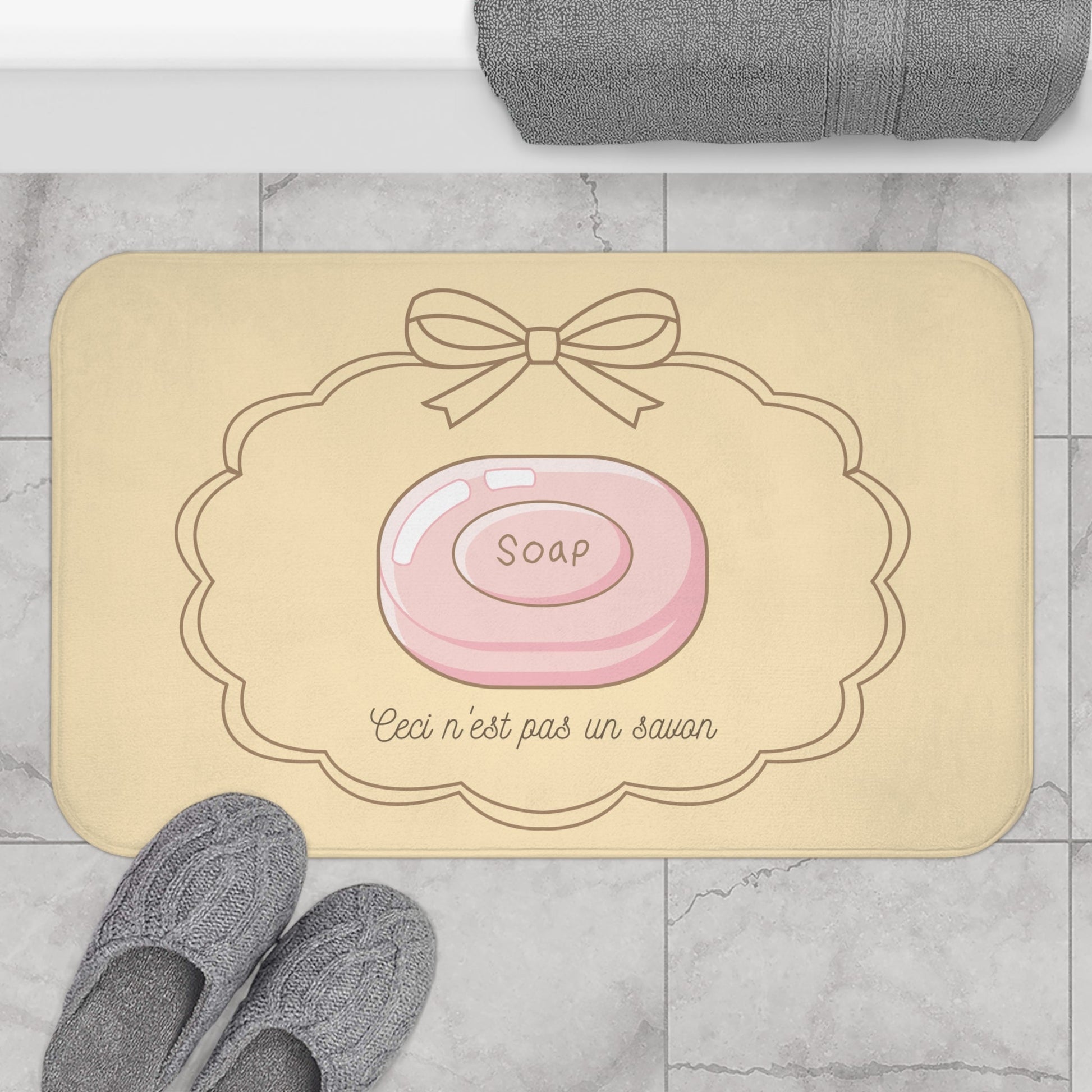 Beige bath mat with soap illustration and text on a bathroom floor.