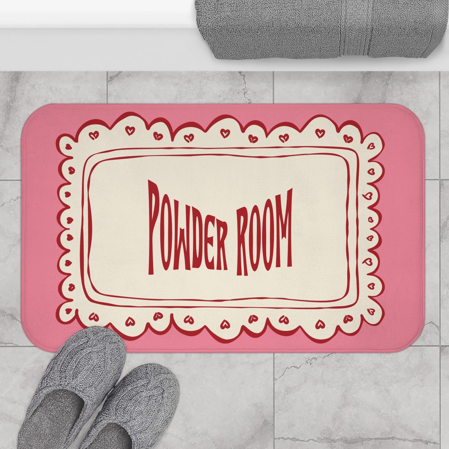 Pink doormat with 'Powder Room' text on a marble floor.