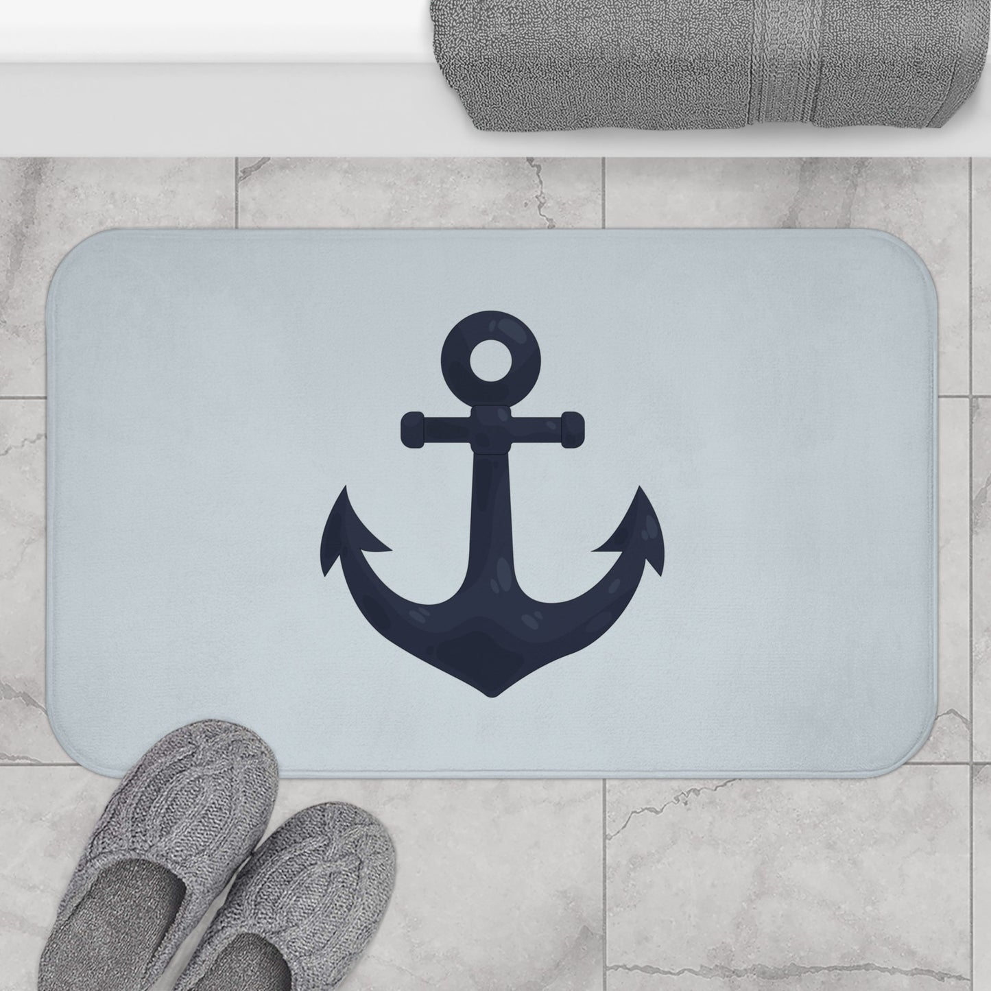 Bath mat with anchor design on a marble floor with slippers and towel.