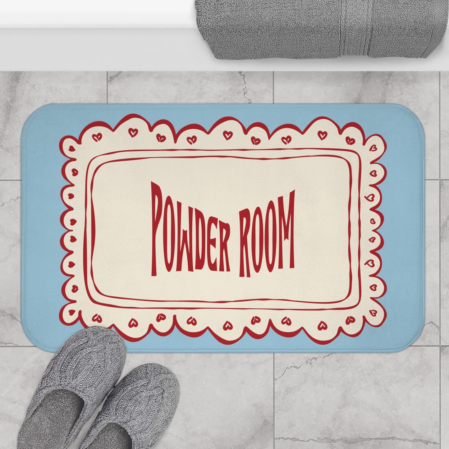 Doormat with 'Powder Room' text on a marble floor with slippers and a towel.