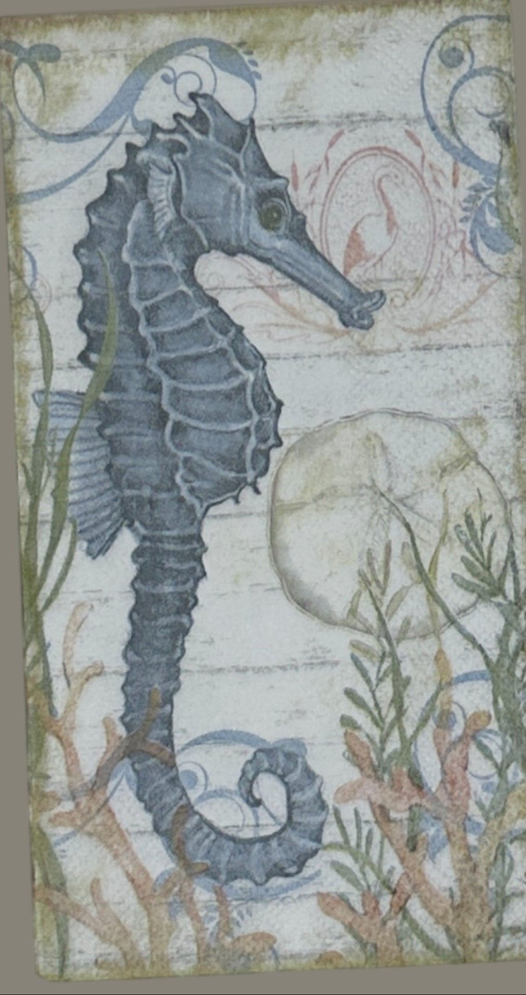 paper napkin with a blue seahorse surrounded by coral seaweed and shells