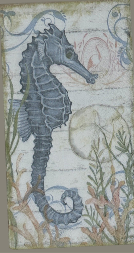 paper napkin with a blue seahorse surrounded by coral seaweed and shells