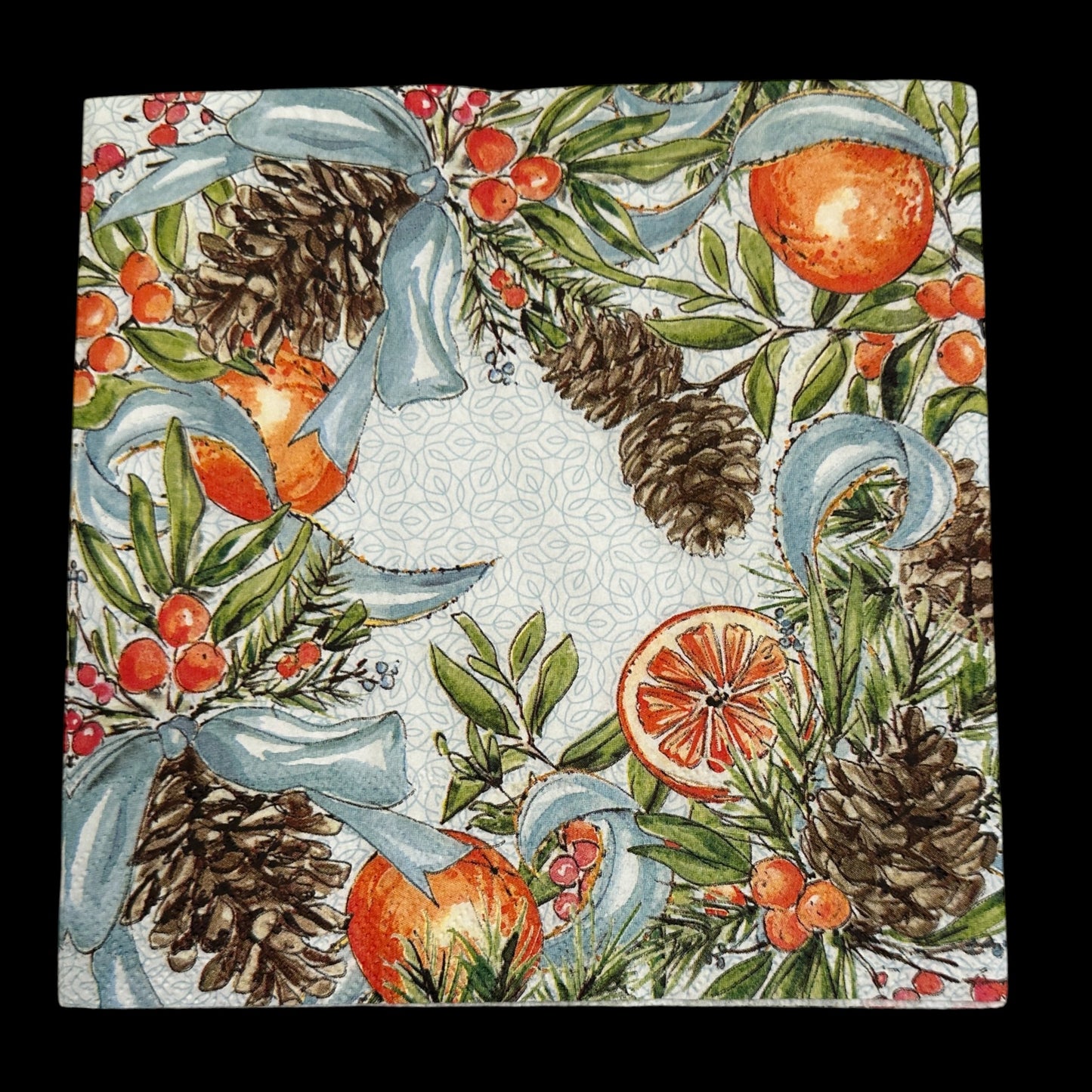 Luncheon size decoupage napkin featuring pinecones, oranges, citrus slices, red berries, and blue ribbons on a white patterned background for holiday crafts.
