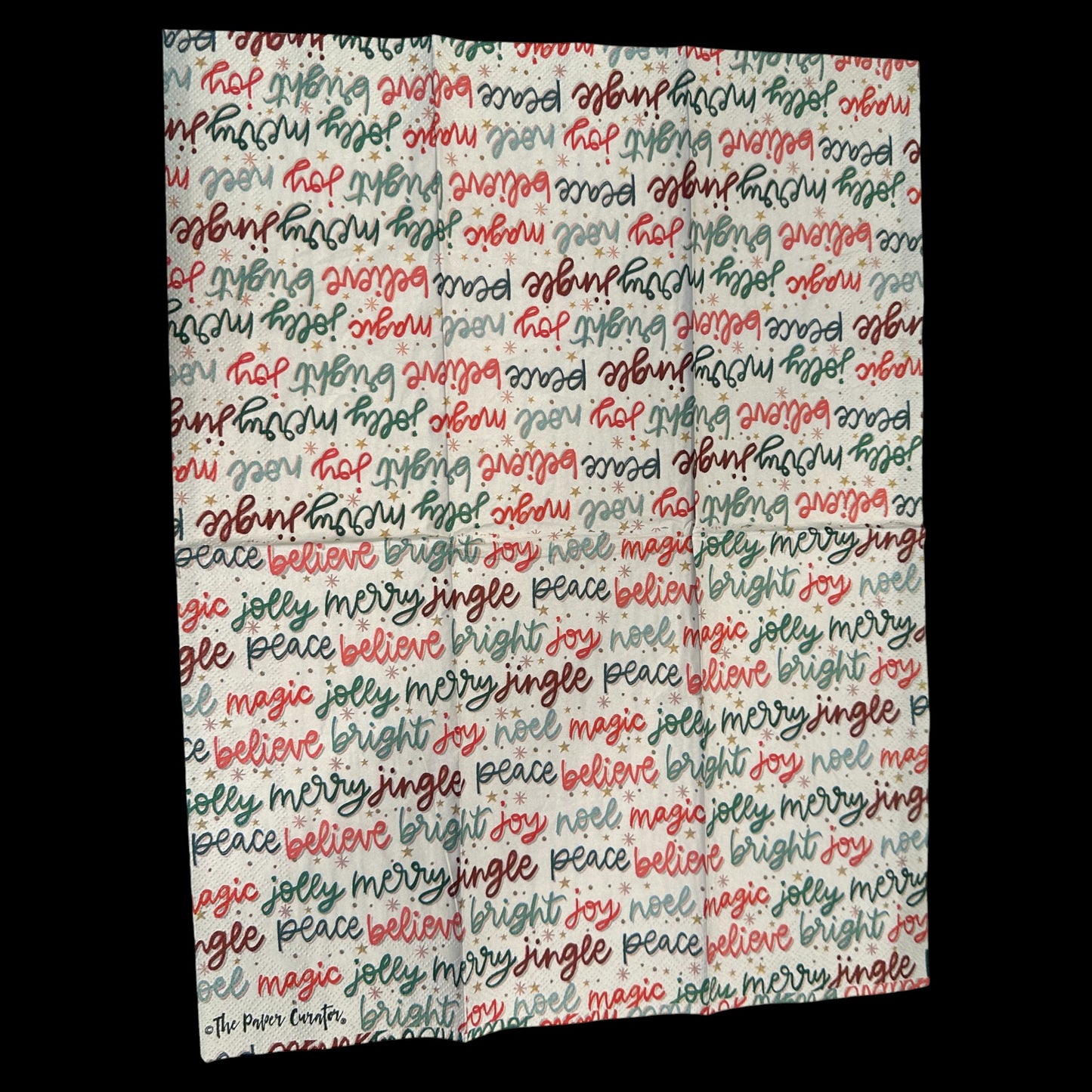 Unfolded Guest size decoupage napkin featuring colorful Christmas word art with phrases like joy, merry, bright, jingle, and believe in red, green, and gold.