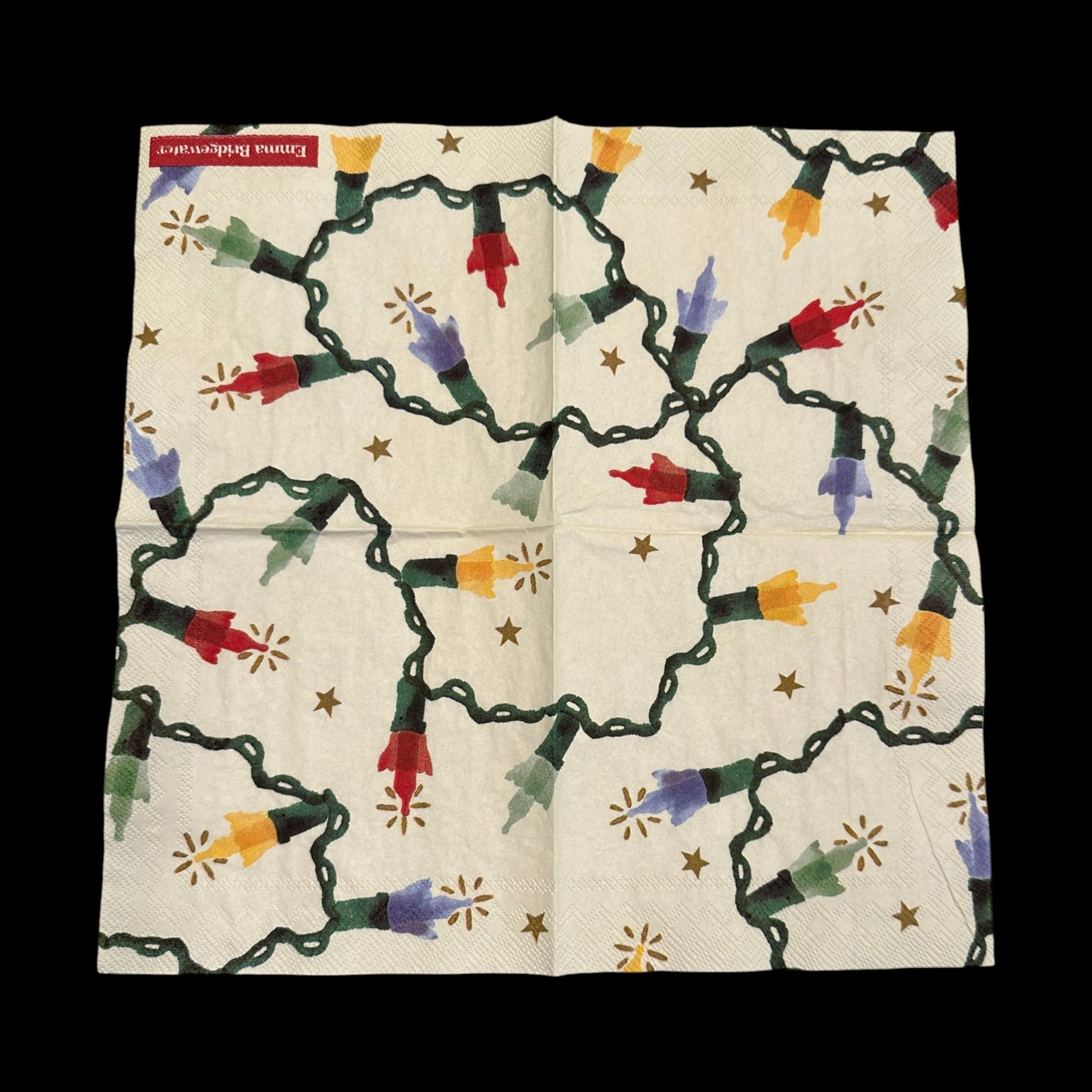 Open Christmas string light decoupage napkin featuring colorful red, yellow, green, and blue bulbs with glowing accents and small gold stars on a cream background.