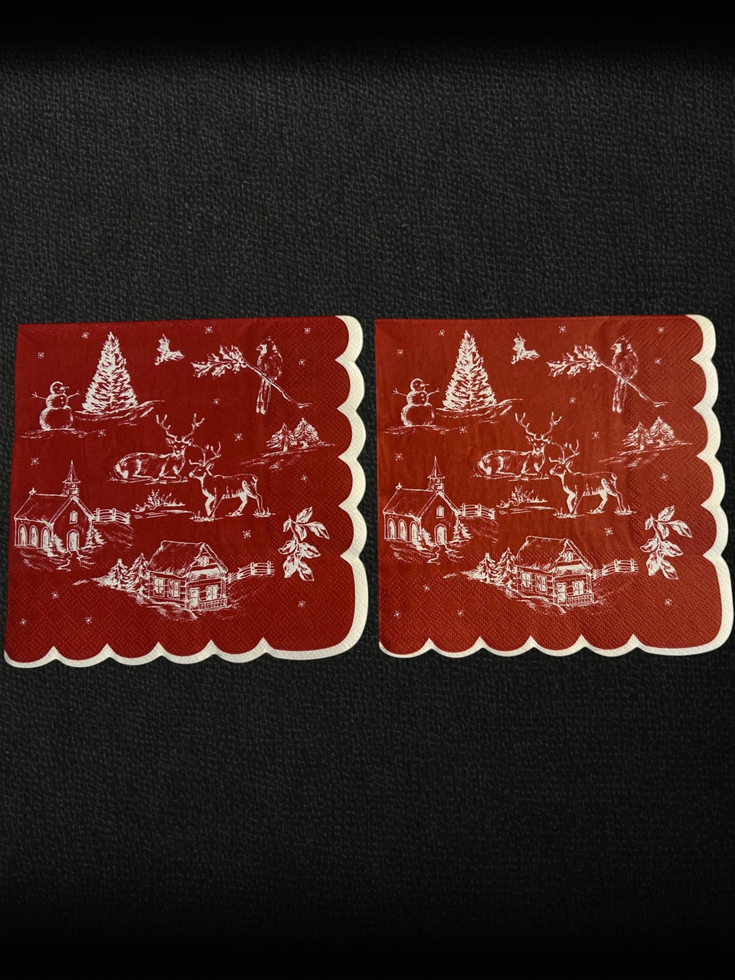 Cocktail size decoupage napkin with scalloped white edge featuring a classic red and white Christmas winter toile scene with snowman deer church cabin cardinal and holly sprigs set of 2