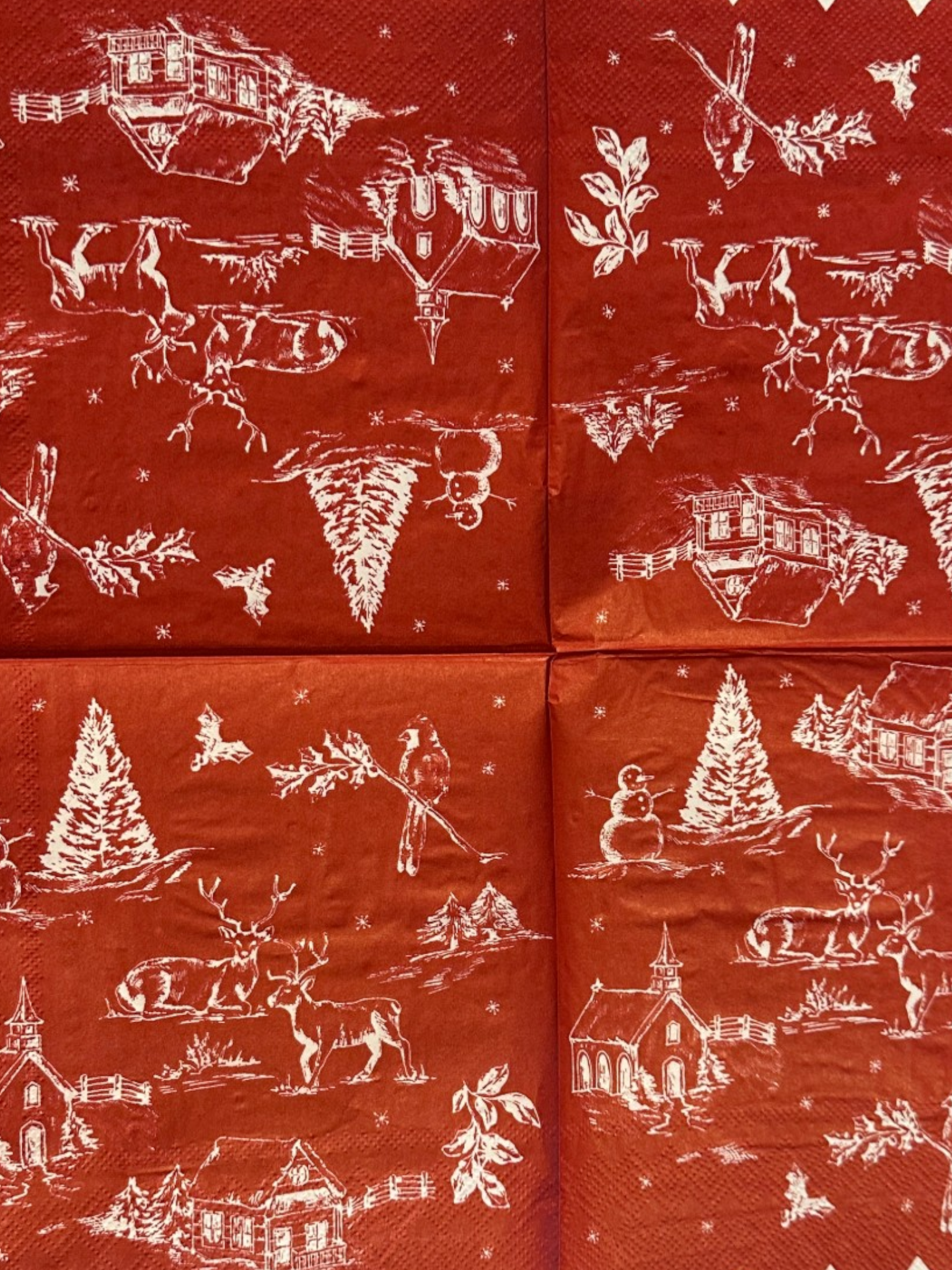 Cocktail size decoupage napkin with scalloped white edge featuring a classic red and white Christmas winter toile scene with snowman deer church cabin cardinal and holly sprigs set of 2