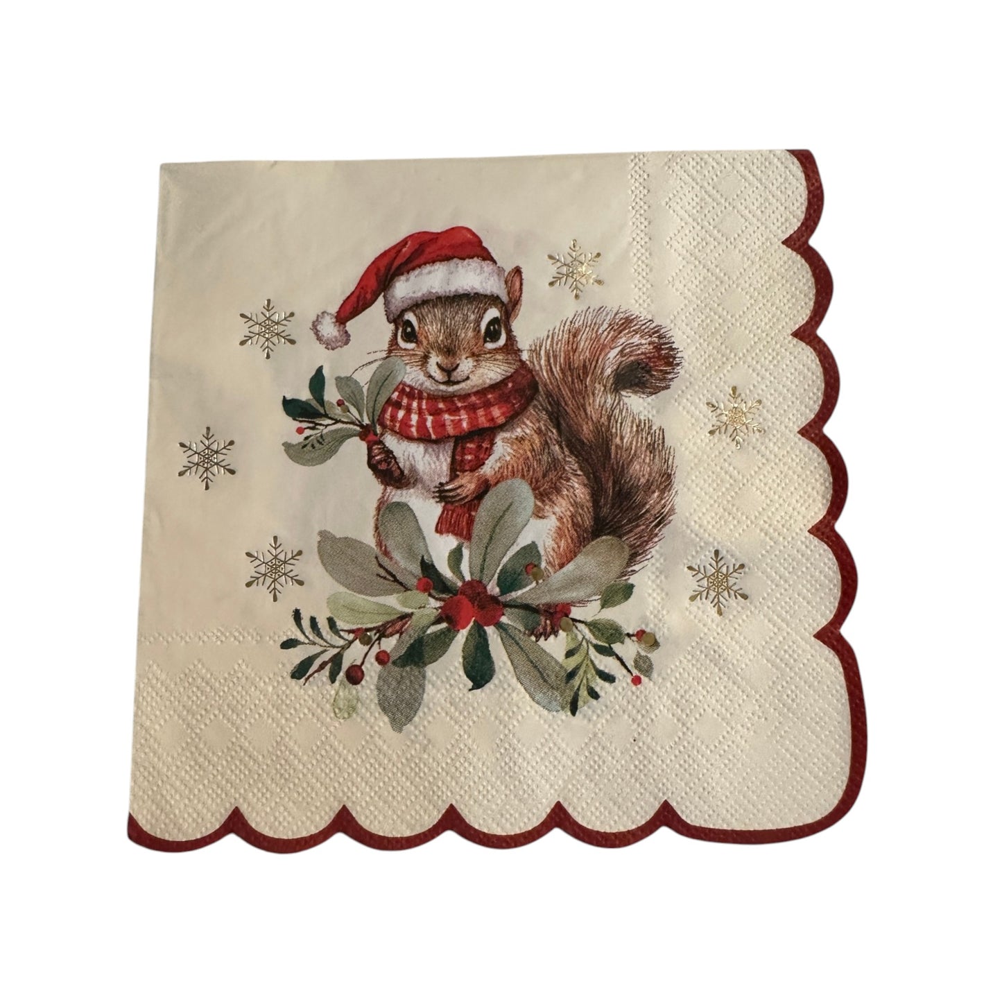A square cream-colored paper napkin with scalloped edges, featuring an illustration of a brown squirrel wearing a red Santa hat and red-and-white plaid scarf, surrounded by green holly leaves, red berries, and small gold snowflakes.
