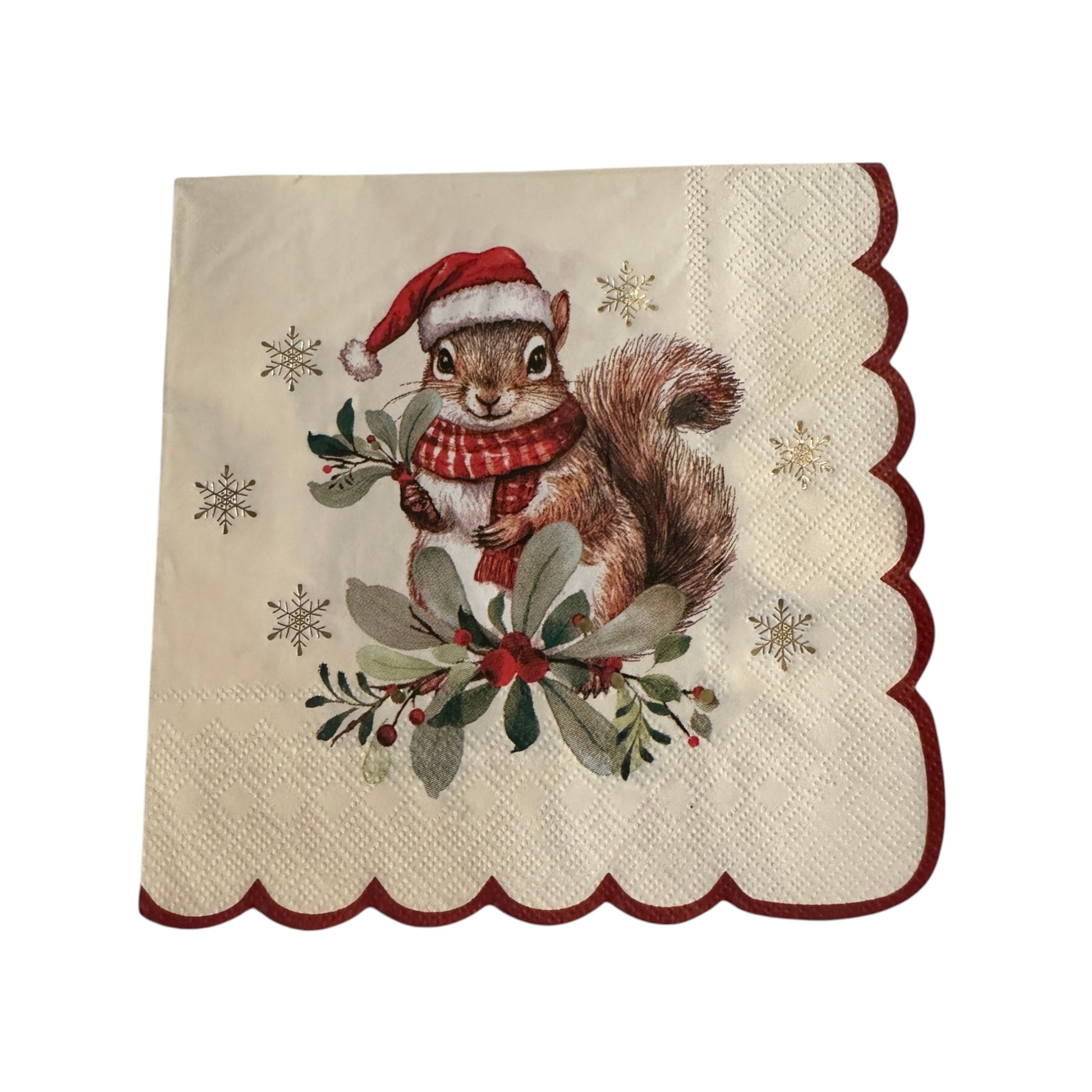 A square cream-colored paper napkin with scalloped edges, featuring an illustration of a brown squirrel wearing a red Santa hat and red-and-white plaid scarf, surrounded by green holly leaves, red berries, and small gold snowflakes.