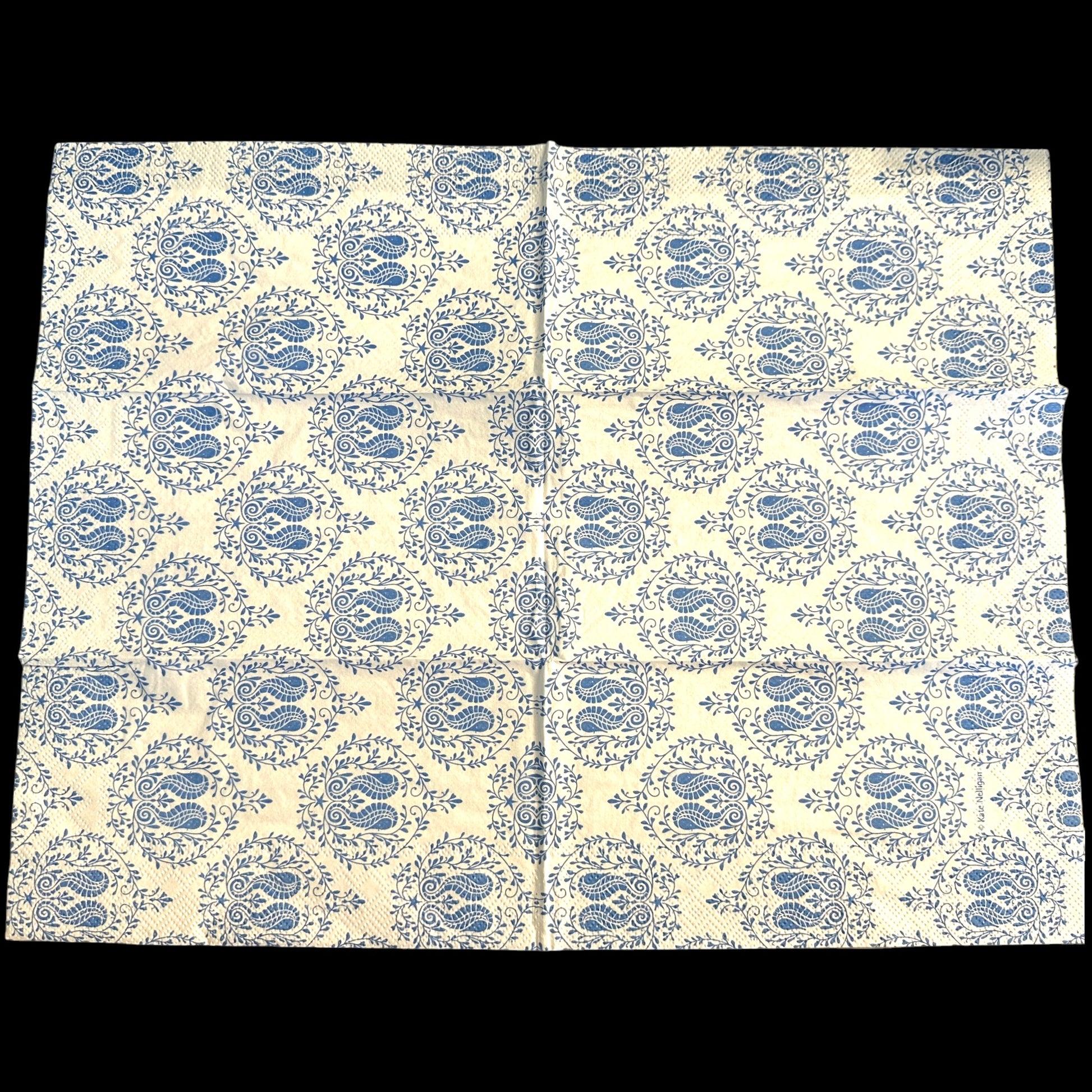 Two guest-size decoupage paper napkins featuring a detailed all-over print of classic paisley teardrops with intricate interior scrollwork and trailing vine and leaf sprigs in rich cobalt and periwinkle blue on a soft warm white background, photographed on a light grey surface.