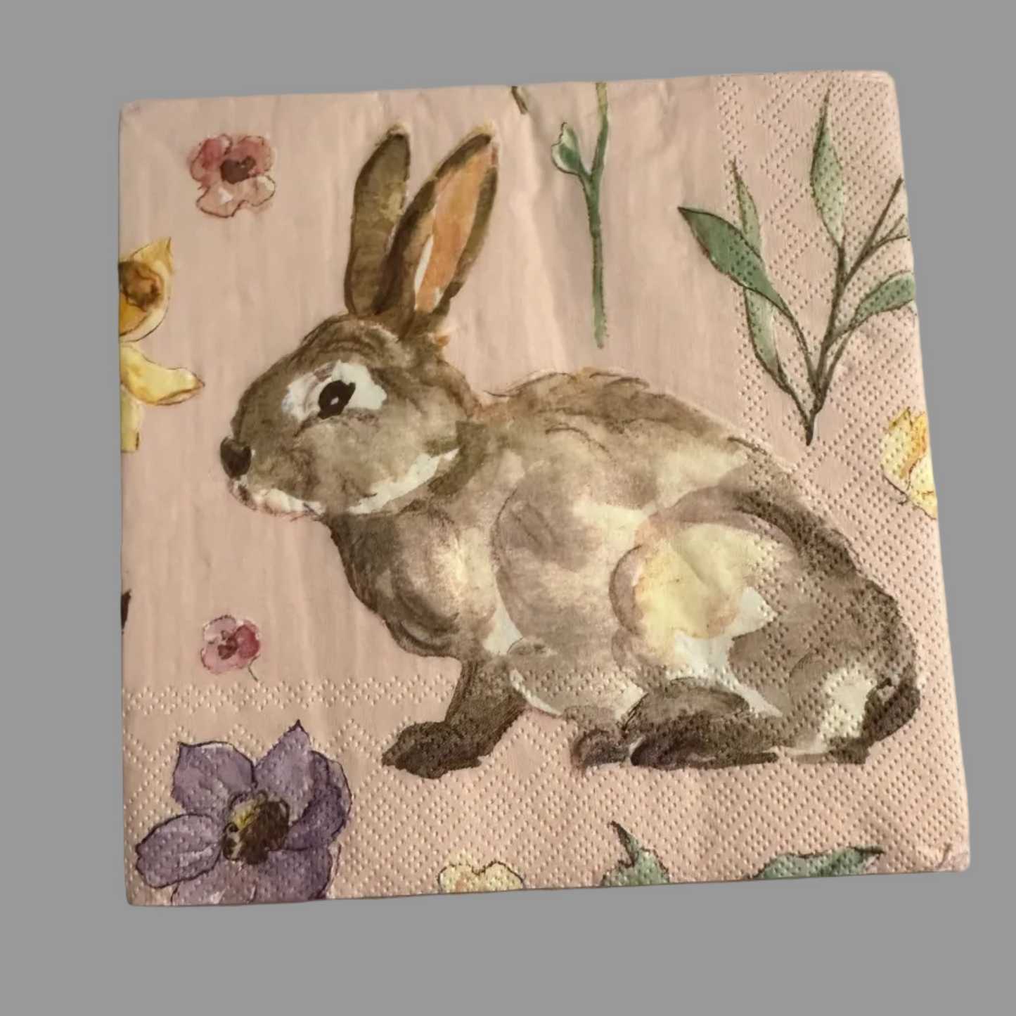 Luncheon size decoupage napkin featuring a watercolor garden bunny surrounded by wildflowers in blush pink lavender and butter yellow on a soft pink background set of 2

