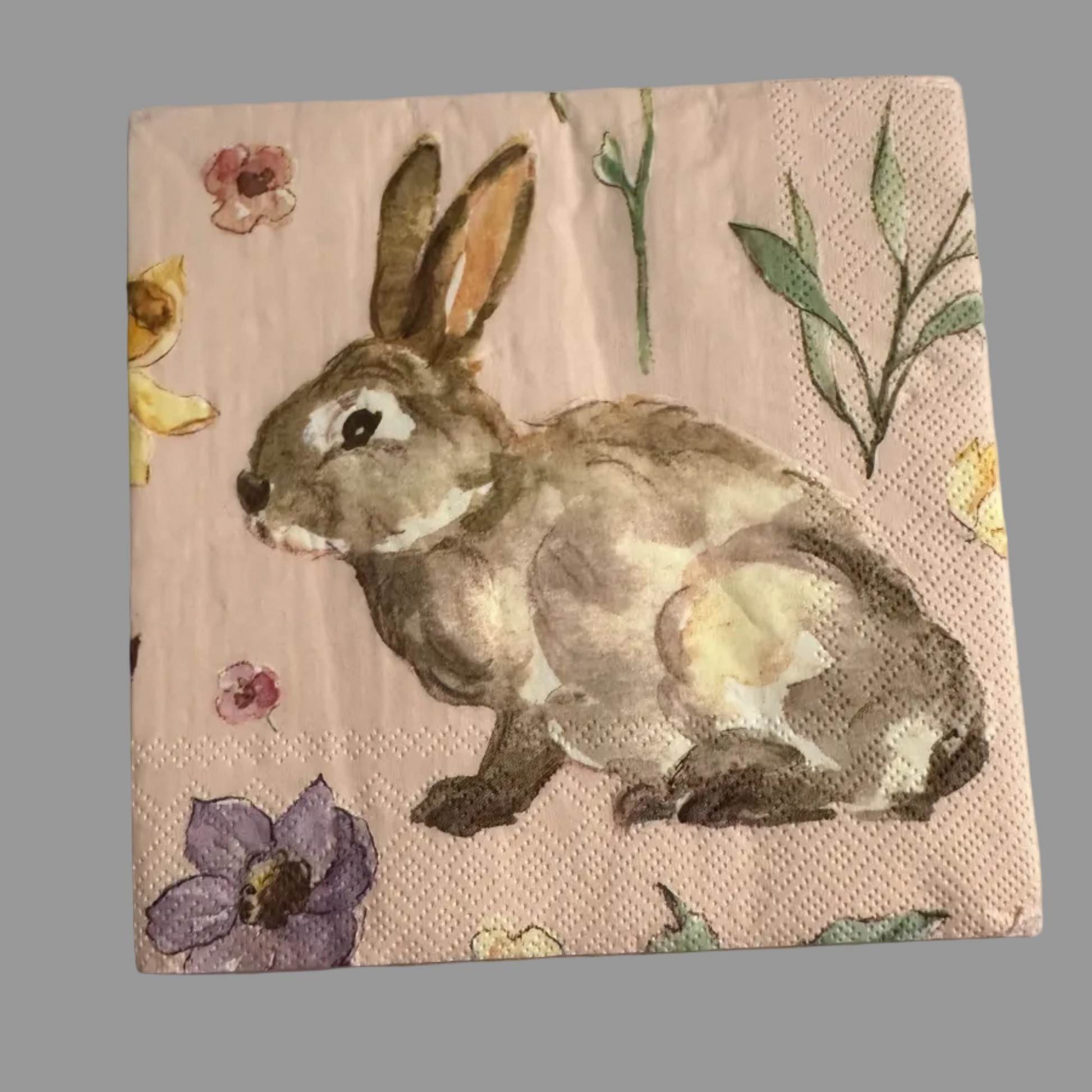 Luncheon size decoupage napkin featuring a watercolor garden bunny surrounded by wildflowers in blush pink lavender and butter yellow on a soft pink background set of 2
