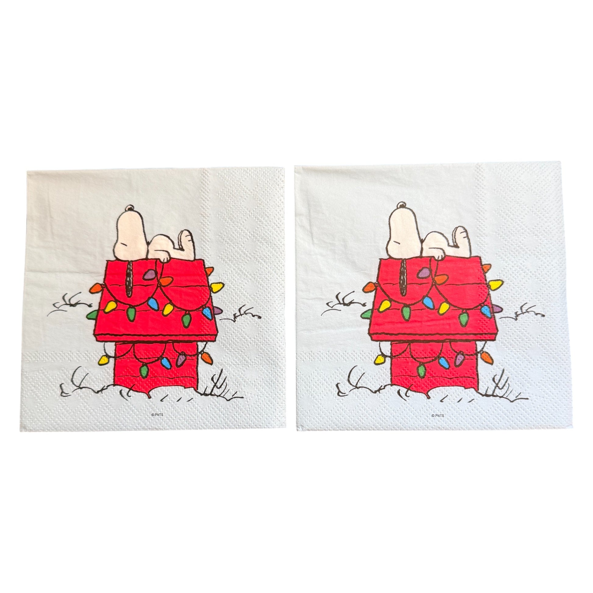 Cocktail size decoupage napkin featuring Snoopy lounging on his red dog house wrapped in colorful multicolored Christmas lights on a white winter background set of 2