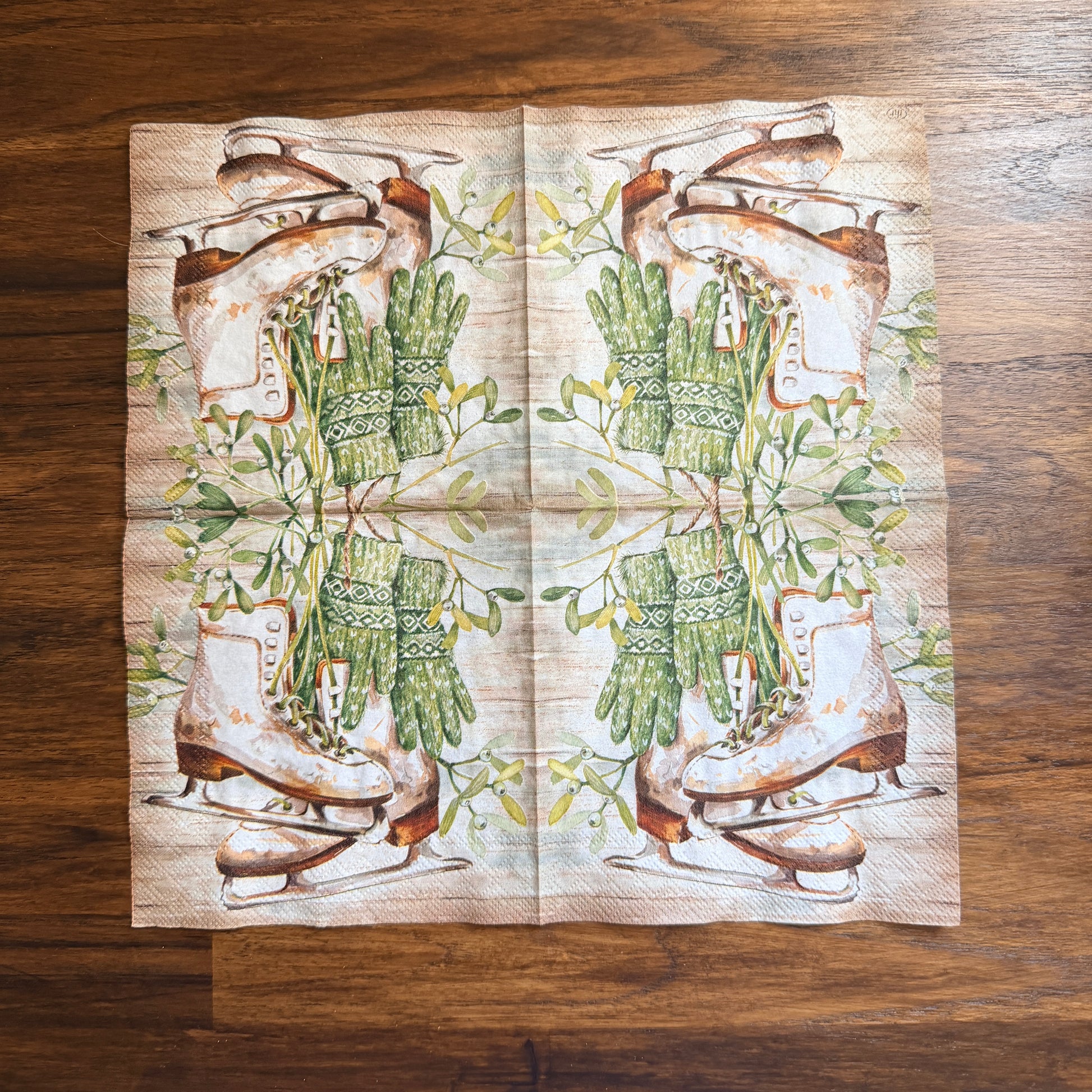 Cocktail size decoupage napkin featuring vintage white leather ice skates with green fair isle mittens hanging from wild mistletoe sprigs on a warm wood grain background set of 2