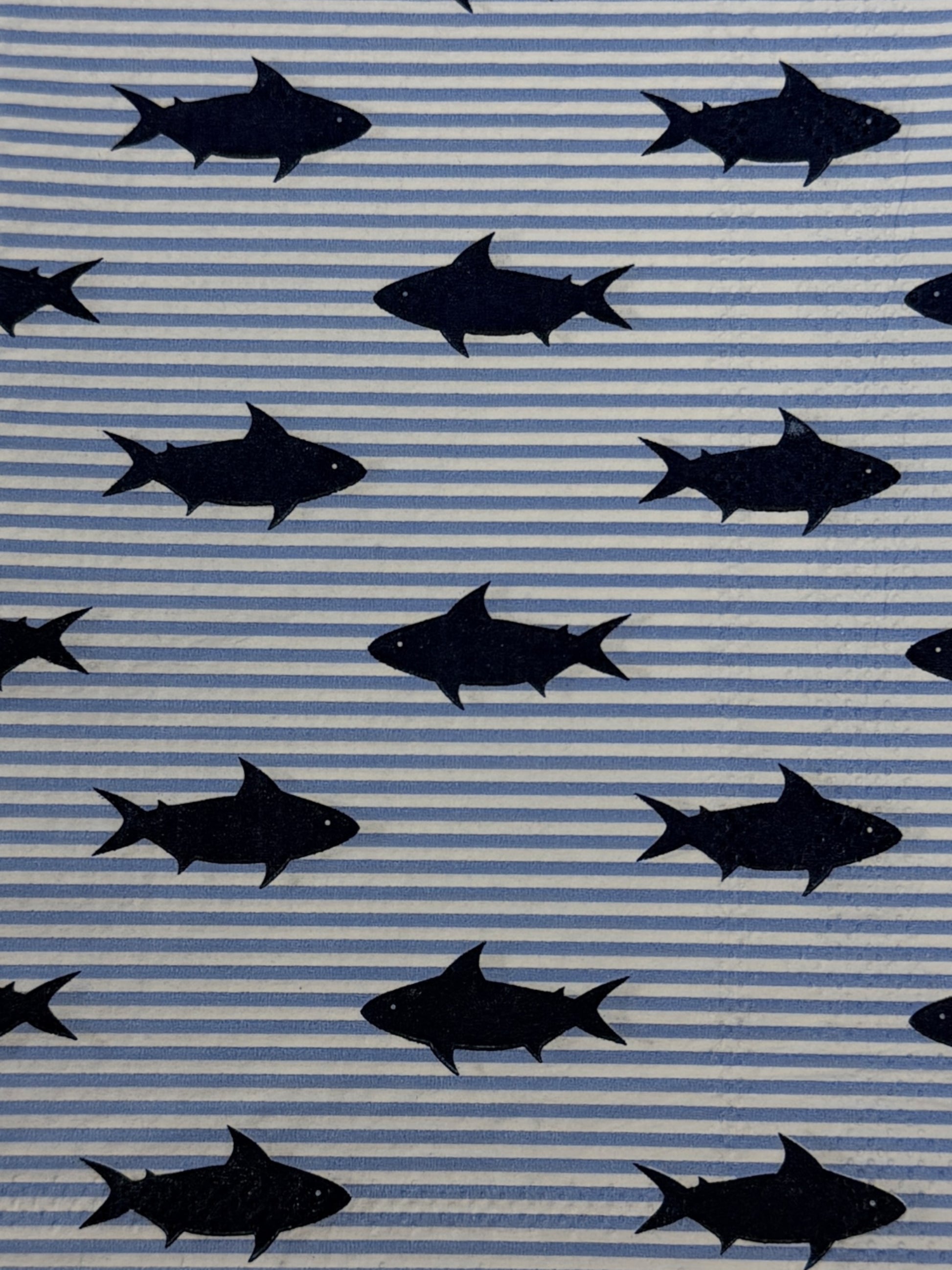 Two guest size decoupage napkins featuring bold navy blue shark silhouettes scattered across a light blue and white pinstripe background set of 2