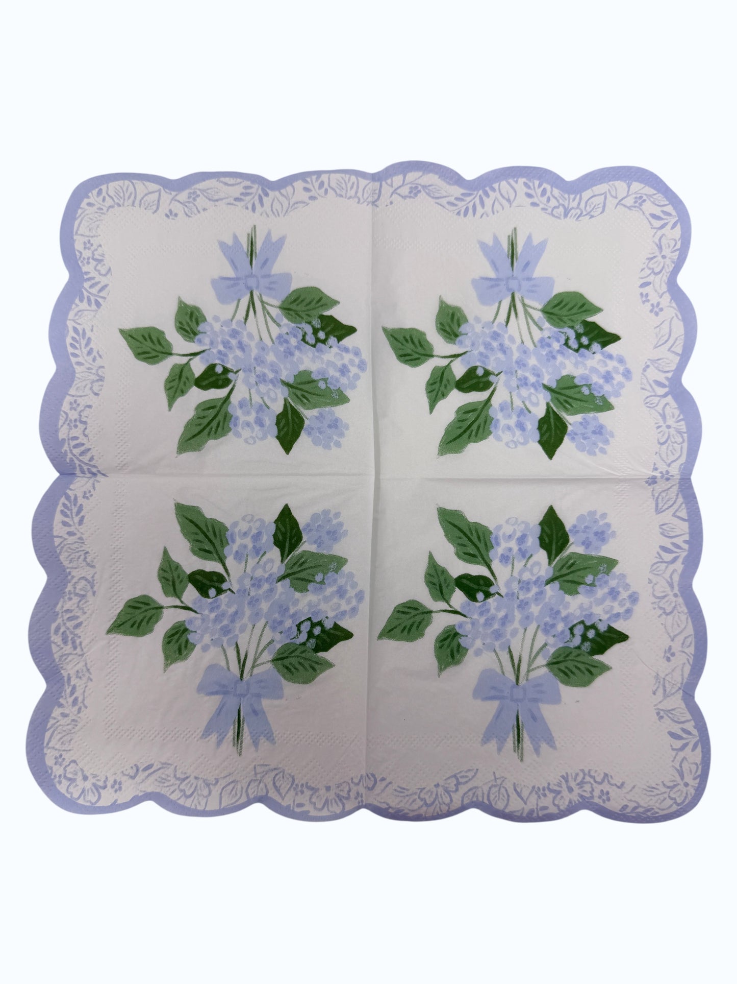 Blue hydrangea scallop edge cocktail napkin with light blue flowers, leafy greens, and floral border unfolded