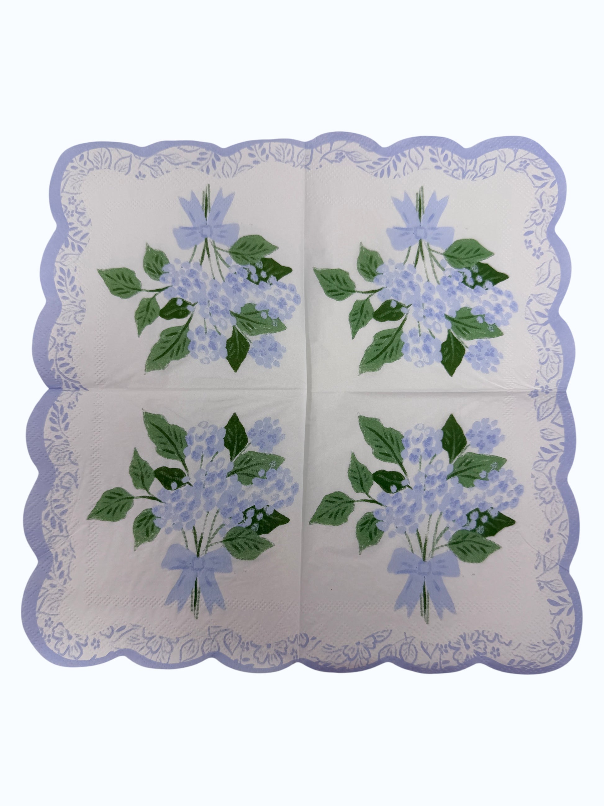 Blue hydrangea scallop edge cocktail napkin with light blue flowers, leafy greens, and floral border unfolded