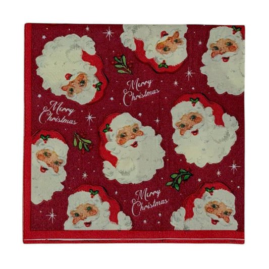Cocktail size decoupage paper napkin featuring multiple jolly vintage Santa face portraits with fluffy white beards and red hats scattered across a deep crimson background with holly sprigs sparkling stars and Merry Christmas script set of 2