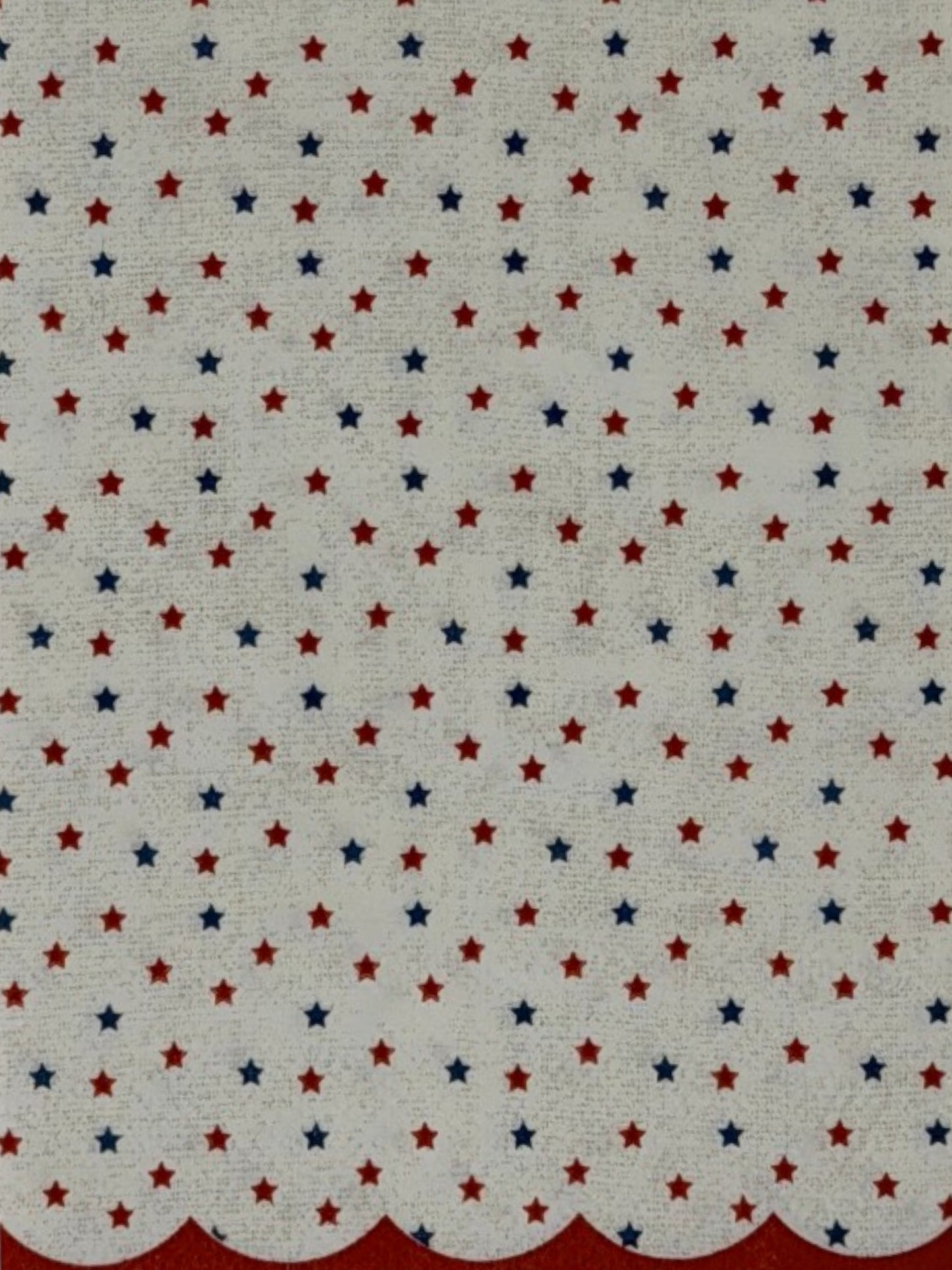 
Guest-size decoupage paper napkin featuring a delicate all-over tossed pattern of tiny red and navy blue stars on a soft warm white background with a charming red scalloped edge border, photographed on a white surface.