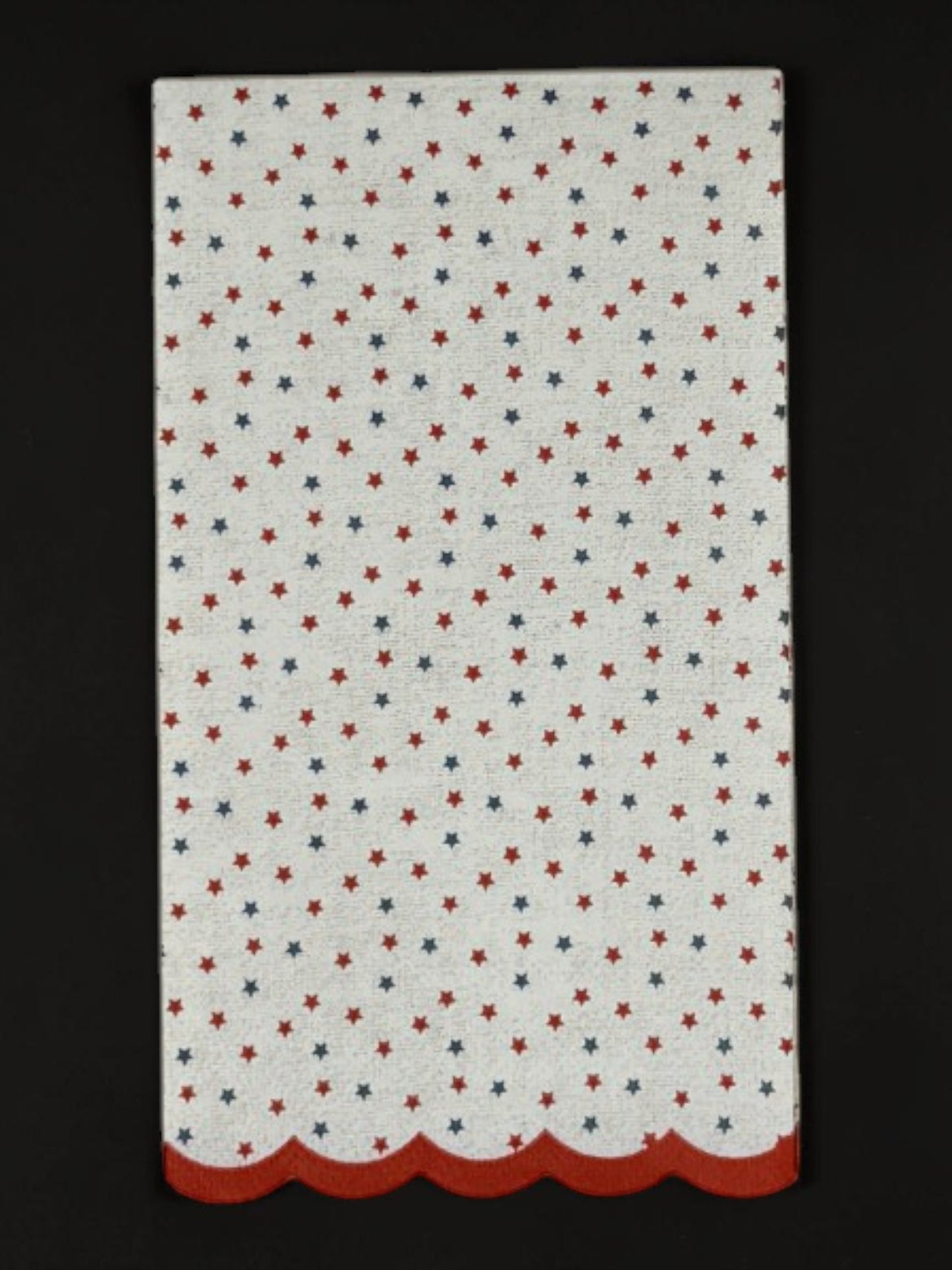 
Guest-size decoupage paper napkin featuring a delicate all-over tossed pattern of tiny red and navy blue stars on a soft warm white background with a charming red scalloped edge border, photographed on a white surface.