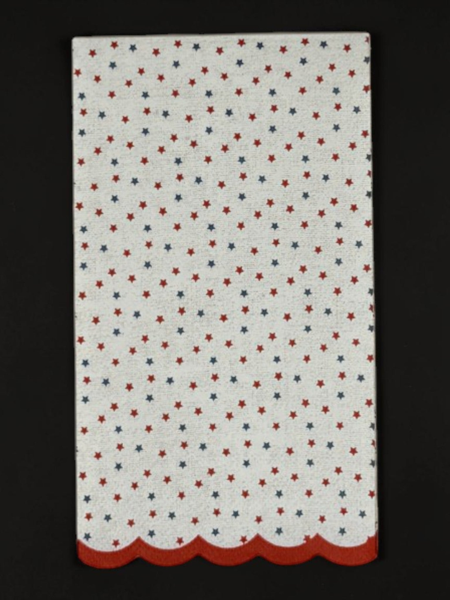 
Guest-size decoupage paper napkin featuring a delicate all-over tossed pattern of tiny red and navy blue stars on a soft warm white background with a charming red scalloped edge border, photographed on a white surface.