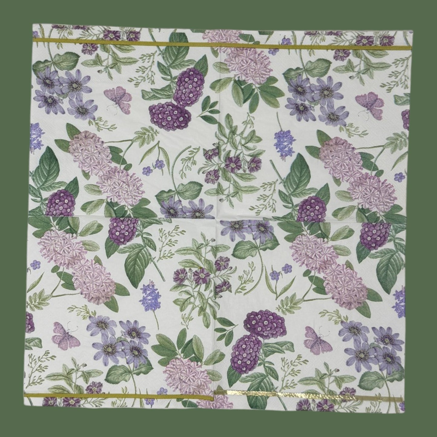 Luncheon-size decoupage paper napkin featuring a vintage botanical illustration print of lavender and purple lilac clusters, periwinkle blue anemones, mauve wildflowers, tiny purple butterflies, and green leaves on a white background with gold foil border stripes, photographed against a white wall.