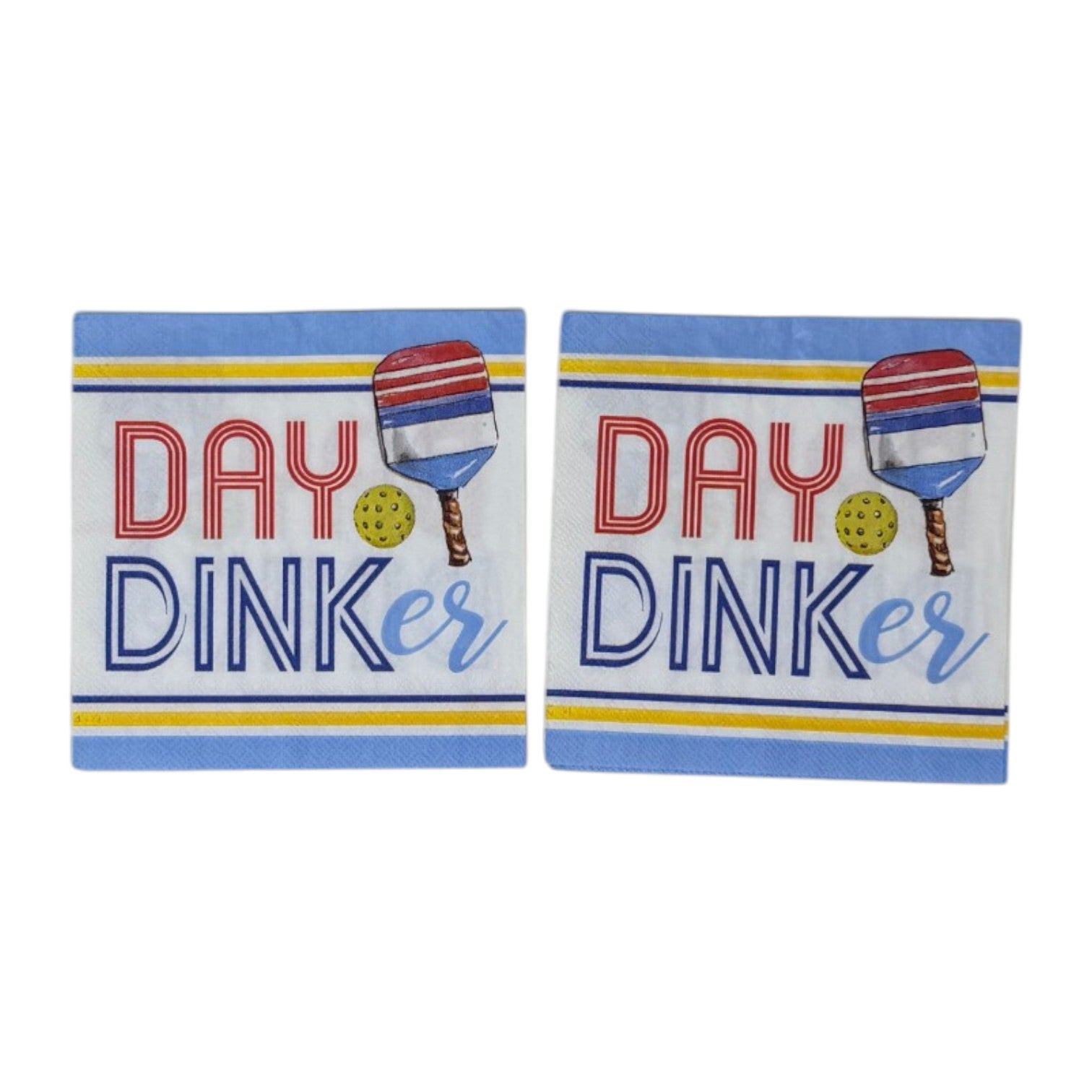 Two cocktail-size decoupage paper napkins featuring a bold graphic design with the phrase DAY DINKer in red and navy lettering alongside a red white and blue pickleball paddle and yellow ball, framed by periwinkle blue and yellow stripe borders on a white background, photographed on a white wall