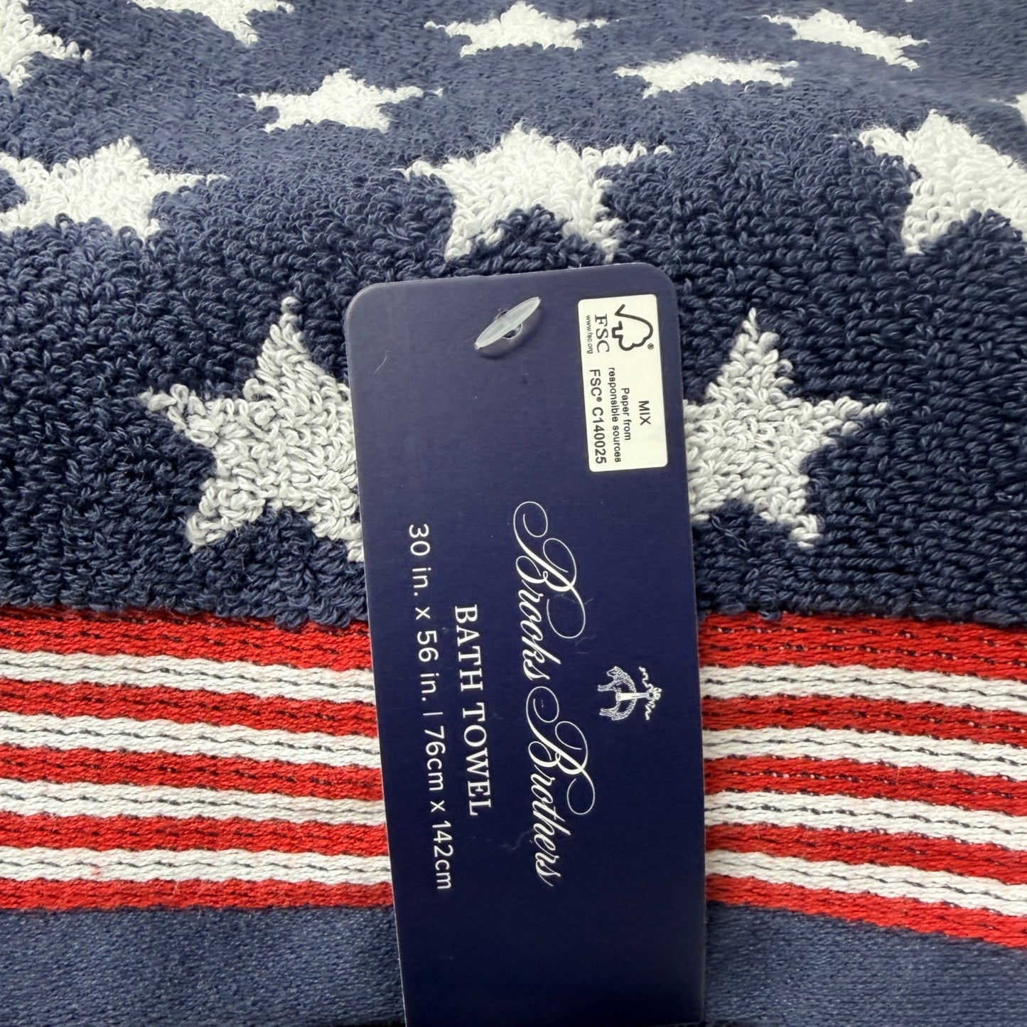Set of two Brooks Brothers navy blue bath towels with all-over white star jacquard pattern and red and white stripe border, 30x56 inches, new with tags