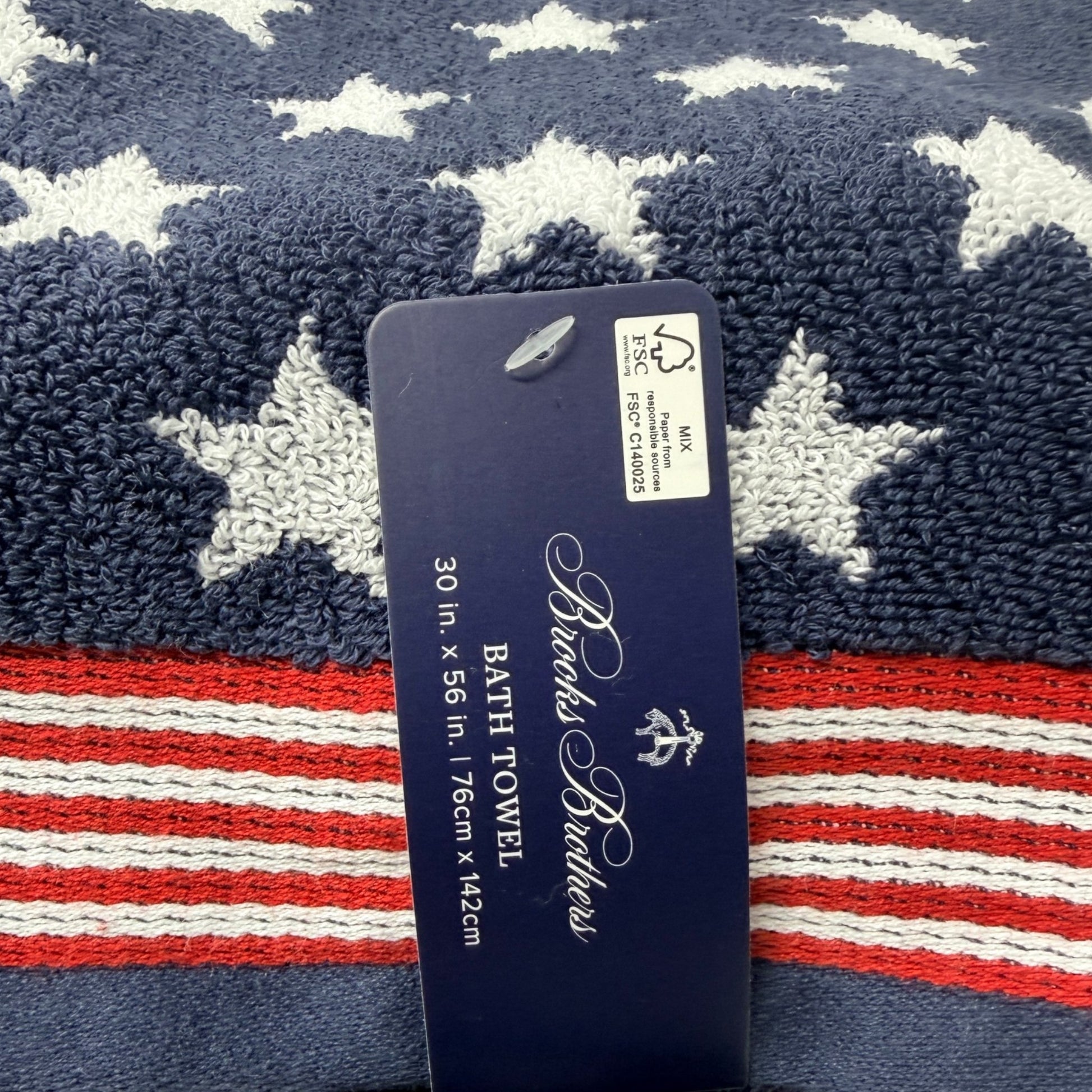Set of two Brooks Brothers navy blue bath towels with all-over white star jacquard pattern and red and white stripe border, 30x56 inches, new with tags