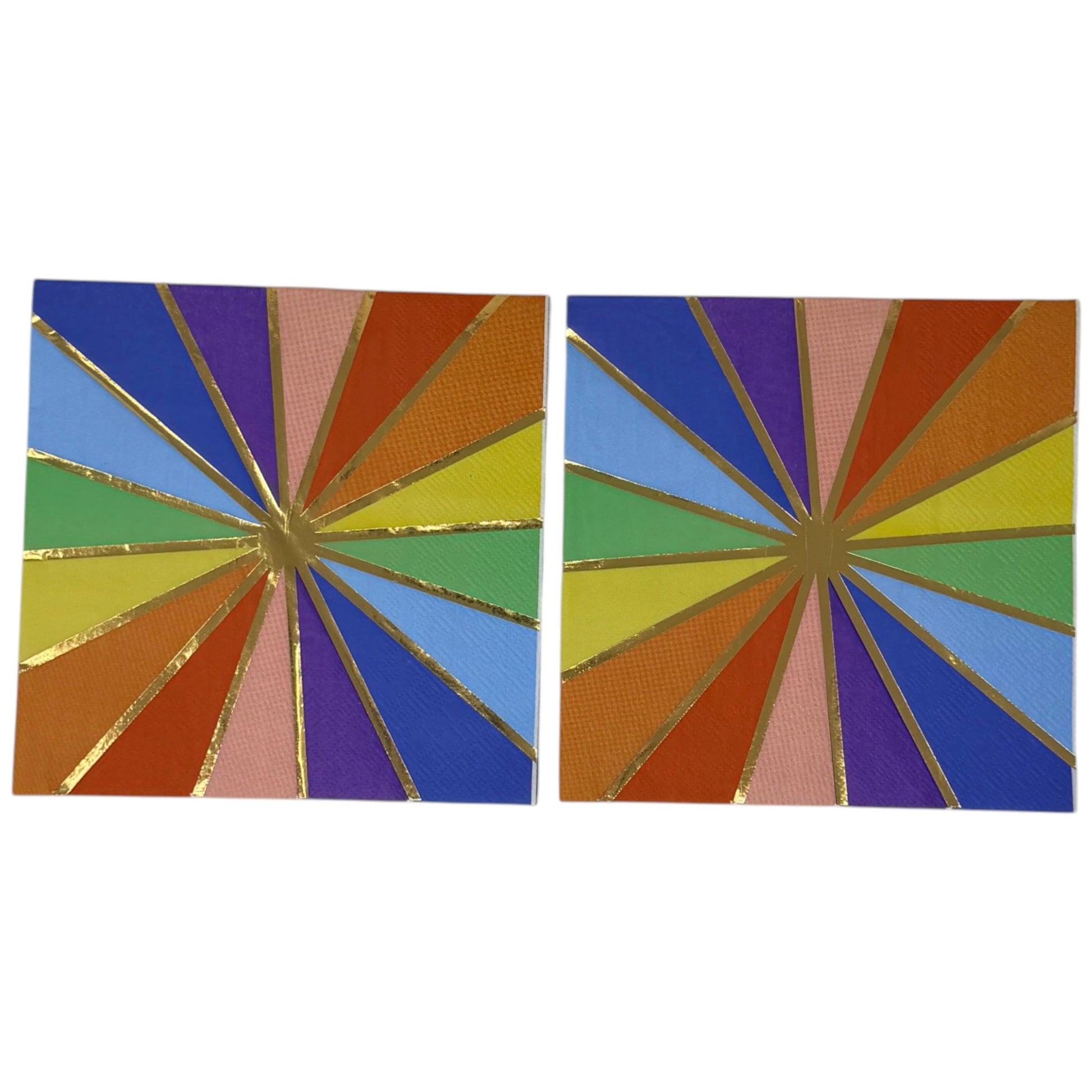 Luncheon-size decoupage paper napkin featuring a bold kaleidoscope pattern of four radiating starburst medallions in cobalt blue, purple, coral, burnt orange, golden yellow, green, and blush pink with crisp white lines and a gold foil starburst accent, photographed unfolded on a light grey surface.