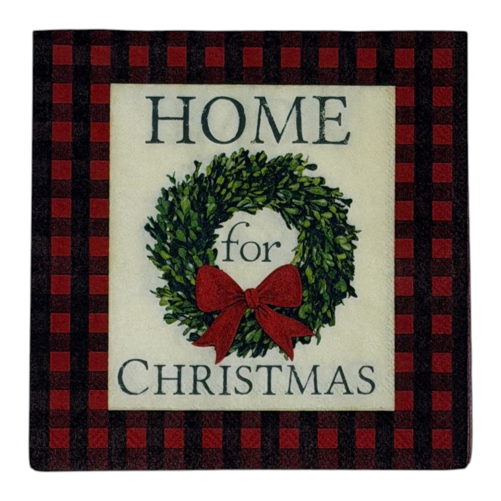 Cocktail-size decoupage paper napkin featuring the phrase Home for Christmas in dark green serif lettering surrounding a lush green boxwood wreath with a full red satin bow on a soft cream ground framed by a deep red and black buffalo check plaid border, photographed on a white surface.