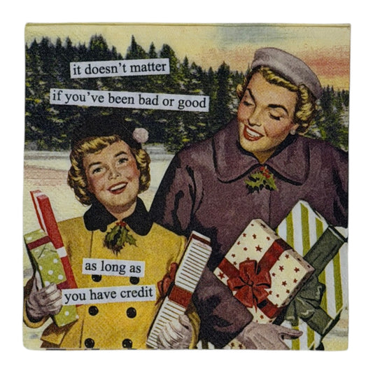 Cocktail-size decoupage paper napkin featuring a classic 1950s style illustration of two cheerful women in yellow and purple winter coats carrying colorful wrapped Christmas gifts outdoors against a snowy pine tree backdrop with a humorous cut-and-paste style caption about holiday shopping and credit, photographed on a white surface.