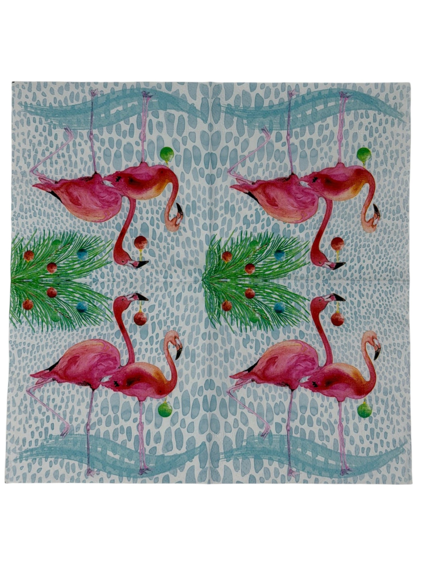 Cocktail-size decoupage paper napkin featuring two watercolor pink flamingos holding colorful Christmas ornaments beneath a pine branch decorated with holiday balls in red teal orange and green on a soft white pebble textured background, photographed on a white surface.