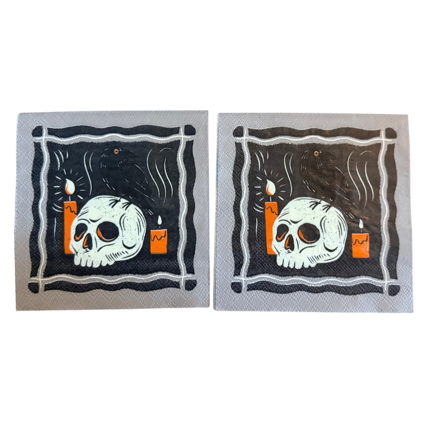 Cocktail-size decoupage paper napkin featuring a bold graphic illustration of a bleached skull resting beside glowing orange candles with a sleek black raven perched on top against a deep black background with swirling dark smoke framed by a graphic wavy border on grey, 