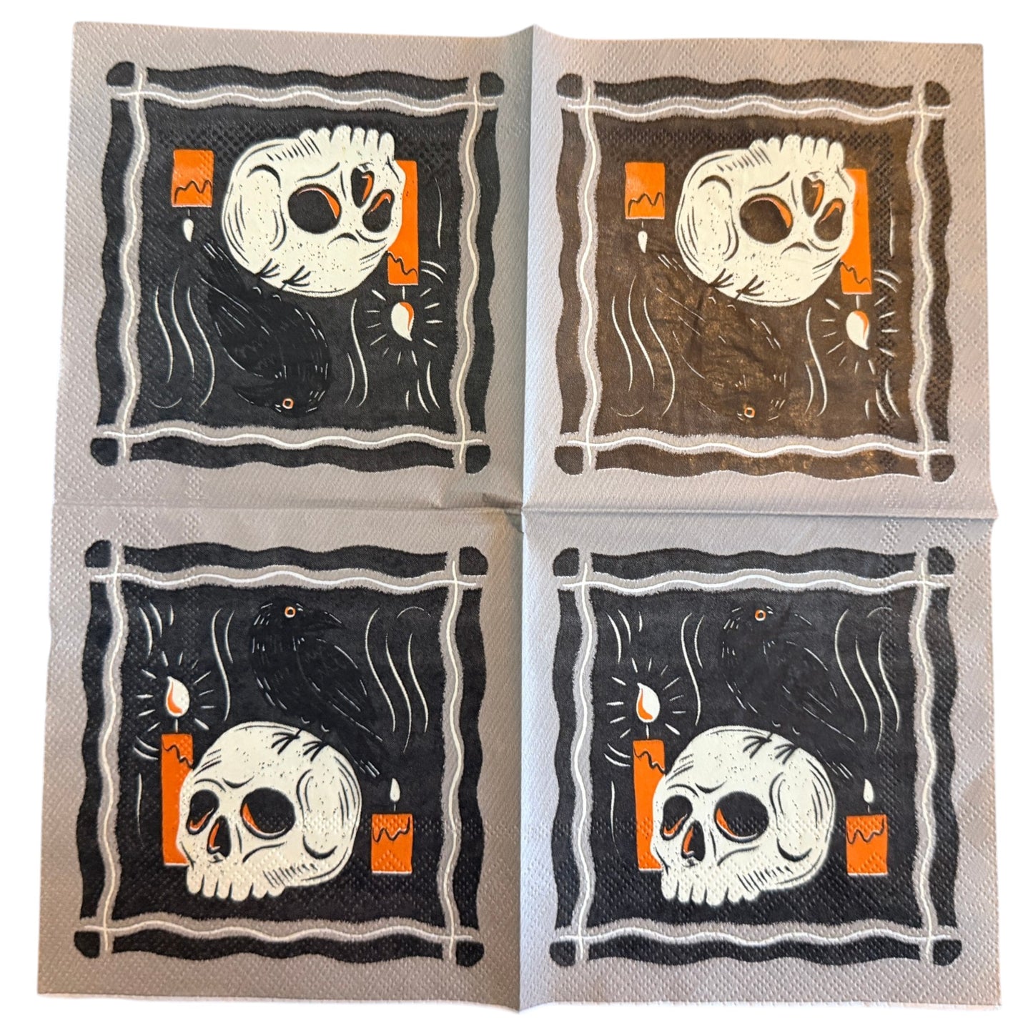 Cocktail-size decoupage paper napkin featuring a bold graphic illustration of a bleached skull resting beside glowing orange candles with a sleek black raven perched on top against a deep black background with swirling dark smoke framed by a graphic wavy border on grey