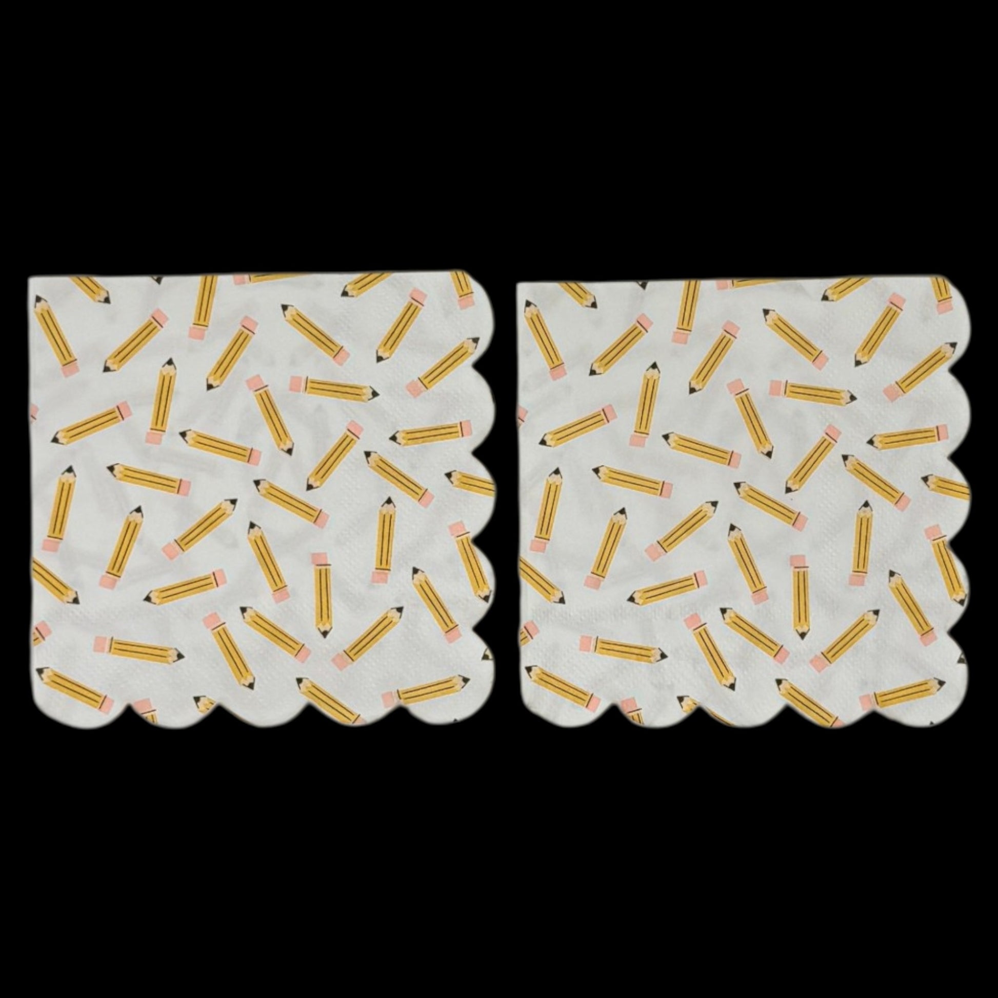 Two cocktail-size decoupage paper napkins featuring an all-over tossed pattern of classic yellow number 2 pencils with pink erasers and sharpened tips scattered in every direction on a crisp white background with a scalloped edge border, photographed on a black surface.