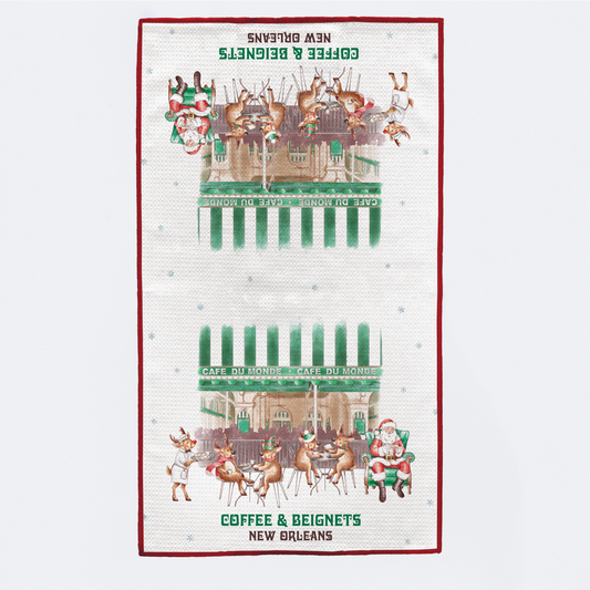 Tea towel with a festive design of a café, reindeer, and Santa Claus on a white background.