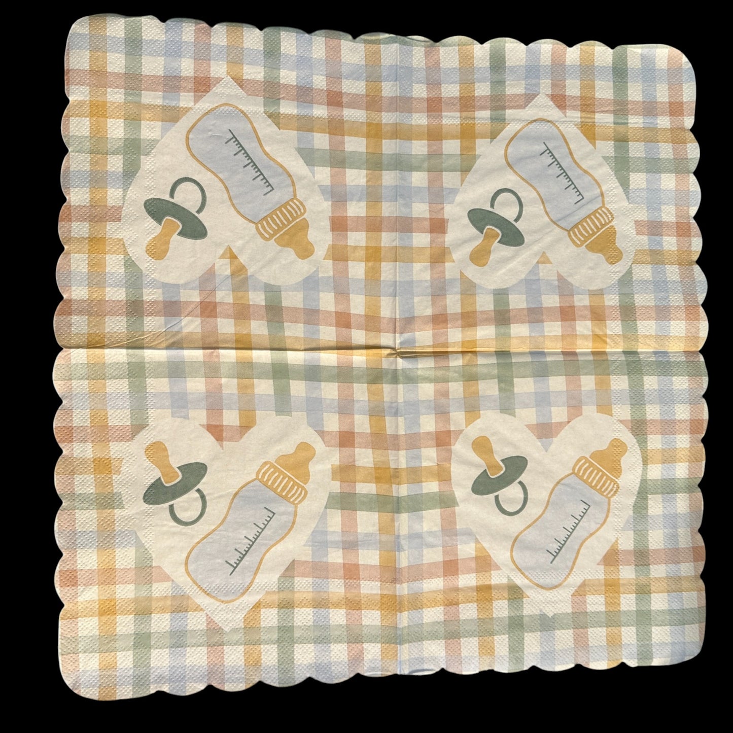 Close-up of an unfolded scalloped-edge luncheon napkin featuring a pastel gingham pattern in yellow, peach, blue, and green with a white heart in the center displaying a baby bottle and pacifier design.