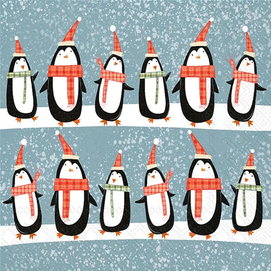 Cocktail size decoupage napkin featuring rows of cute penguins wearing scarves and Santa hats on a snowy blue background for holiday crafts and decor.