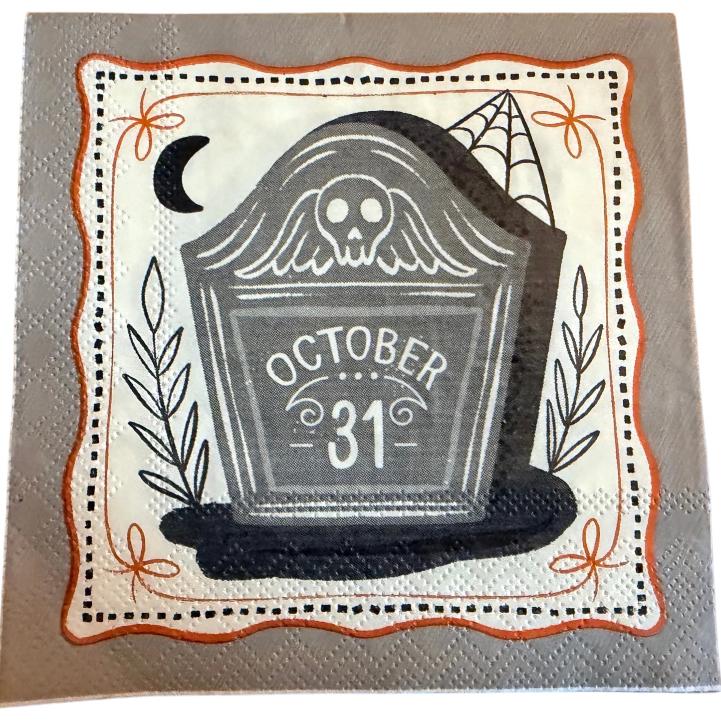Cocktail-size decoupage paper napkin featuring a weathered grey tombstone engraved with October 31 lettering and a ghostly owl illustration with a crescent moon botanical leaf sprigs and a spider web framed by a wavy orange border with bow accents on a soft grey background, 