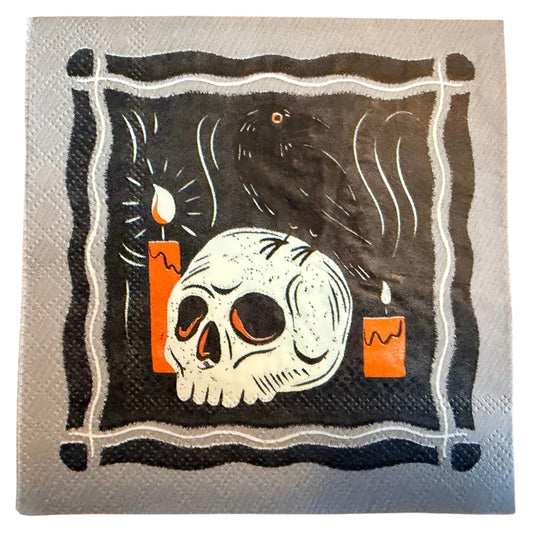 A square paper napkin featuring a gothic illustration of a skull, a raven, and two orange candles on a black background with a white border.