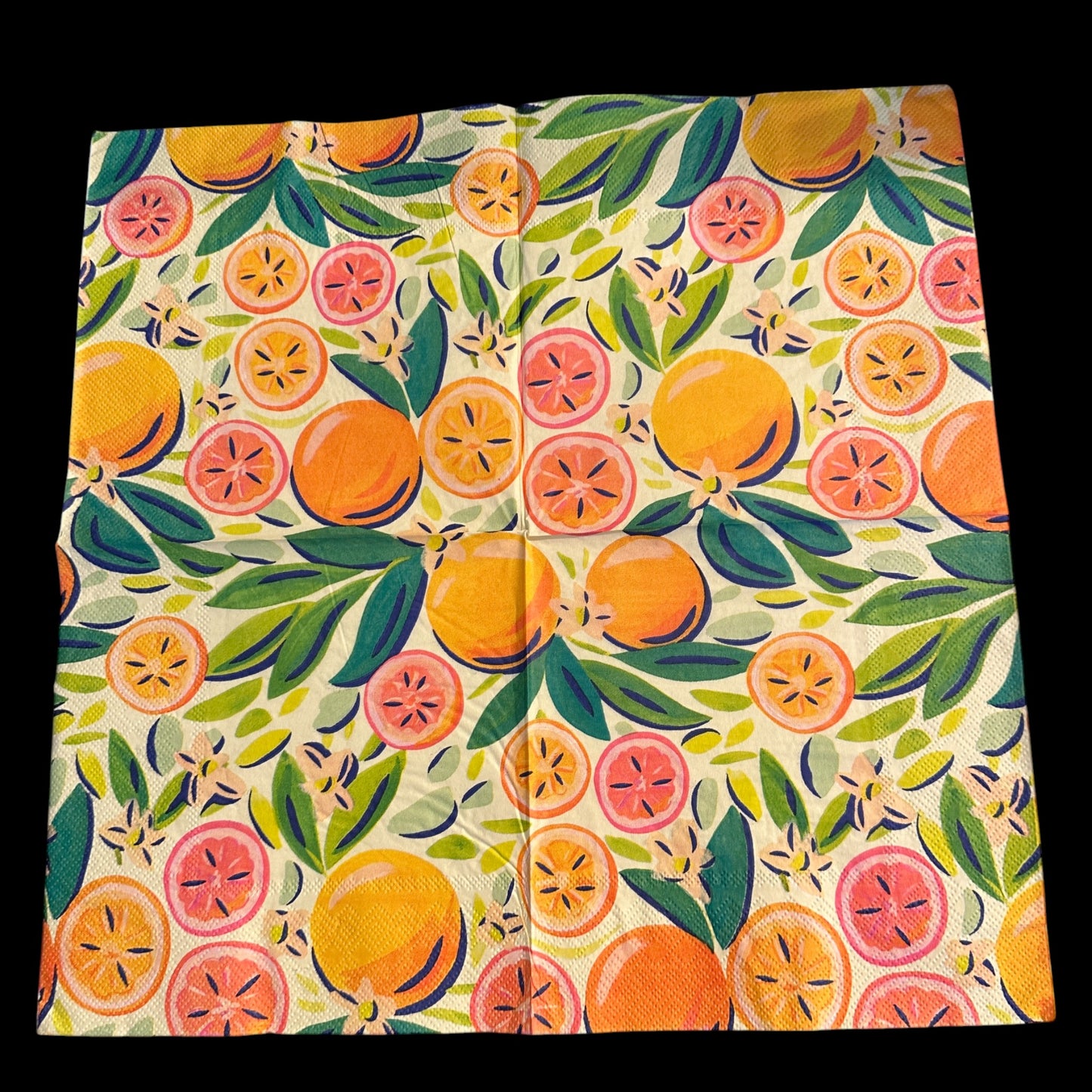 Close-up of an unfolded bright luncheon napkin featuring watercolor oranges, grapefruit, and green leaves designed by Kristen Vogel on a light cream background.