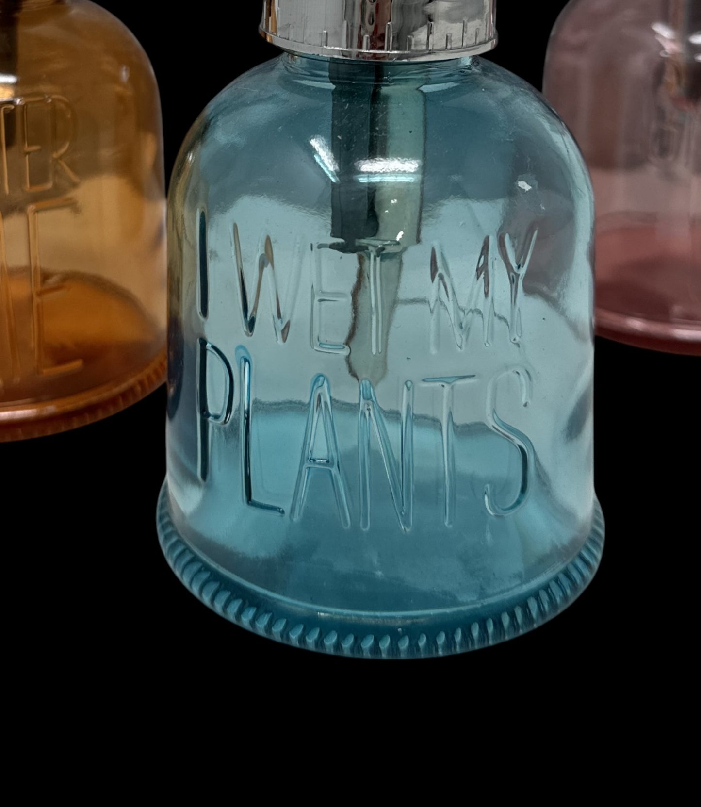 Blue glass bottle with 'I wet my plants' text on a black background